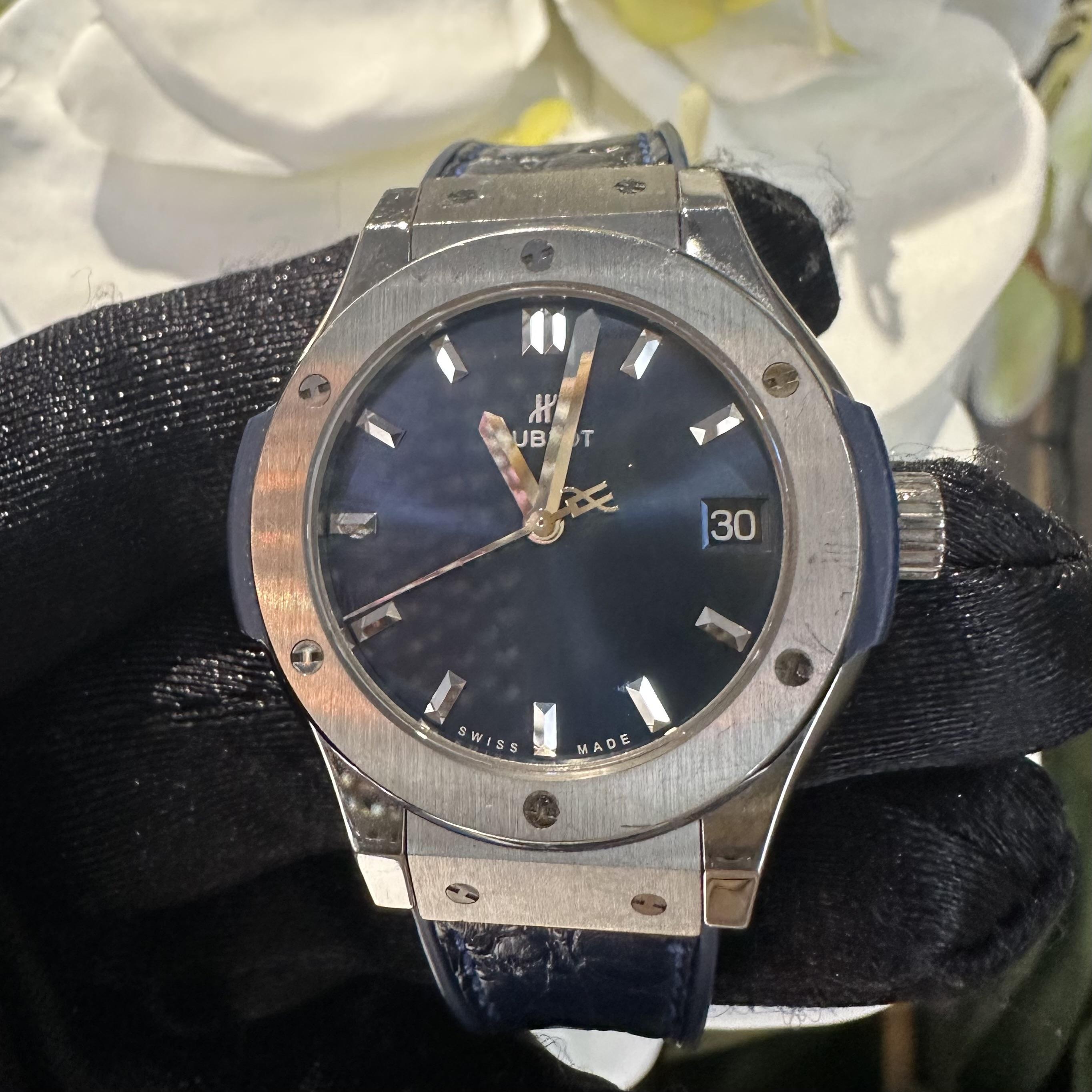BRAND: Hublot 
MODEL NUMBER: 581.NX.7170.LR
MODEL NAME: Classic Fusion
BEZEL: Fixed, Titanium
MOVEMENT: Quartz 
CASE BACK: Solid
MATERIAL: Titanium 
CASE SIZE: 33 mm 
DIAL: Blue, Stick Hour Markers
BRACELET MATERIAL: Rubber/Leather 
COMPLICATION: