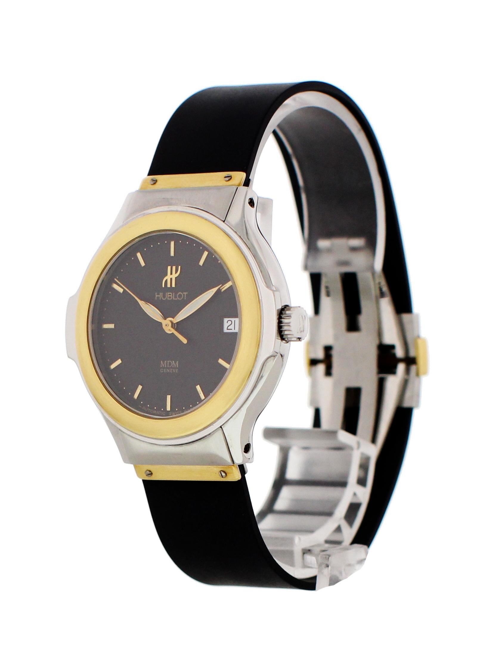 Hublot MDM 1710.2 Automatic Watch. 27 mm stainless steel case. 18k yellow gold bezel and lugs. Black dial with gold hands and index markers. Date display. Black rubber strap with an 18k yellow gold hidden double folding clasp. Will fit up to a