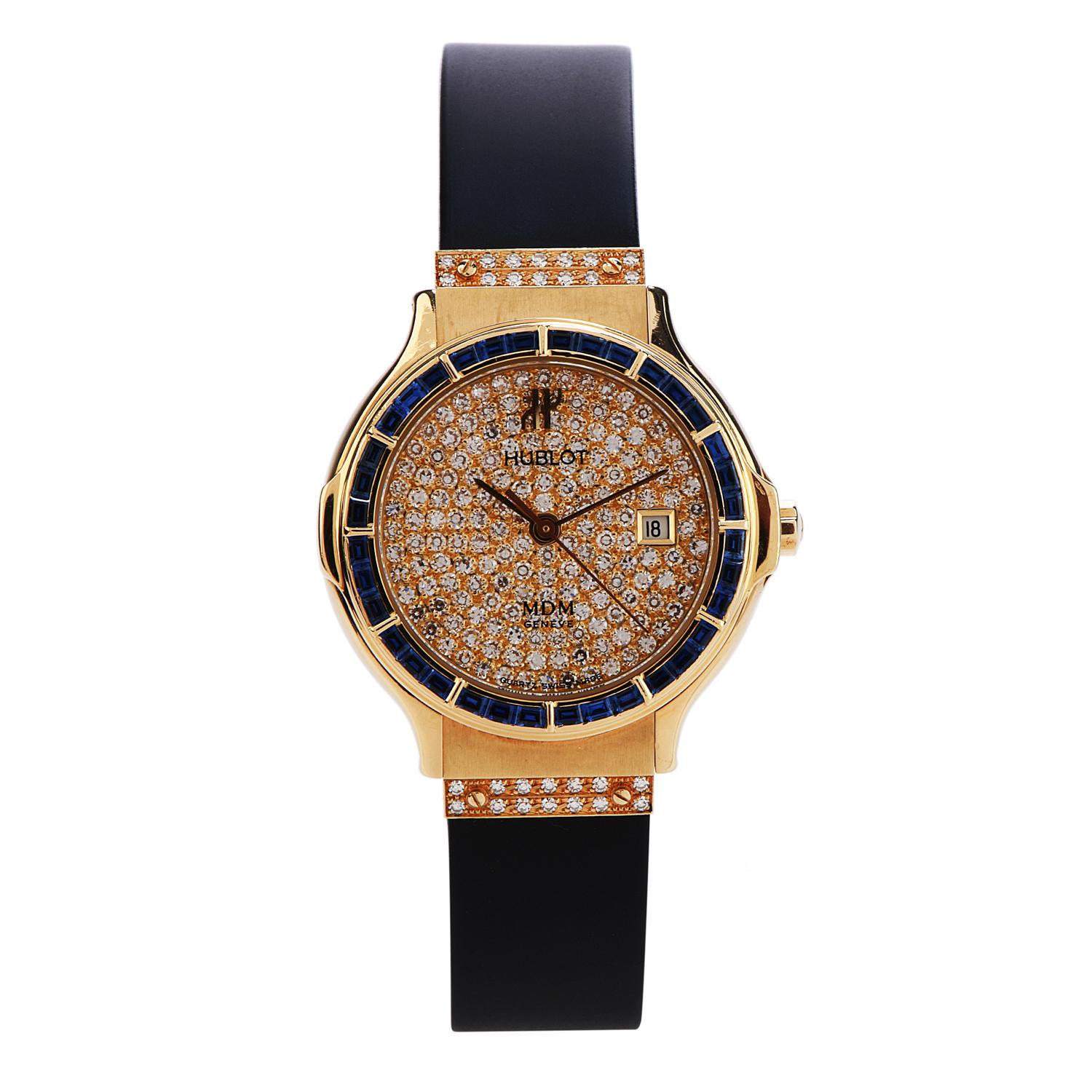This ladies' boutique watch by Hublot features a 28 mm 18k yellow gold case, surrounding a diamond dial on a black rubber strap and factory-set diamond buckle.

The distinctive sapphire bezel, embellished with 36 baguette-shaped blue sapphires,