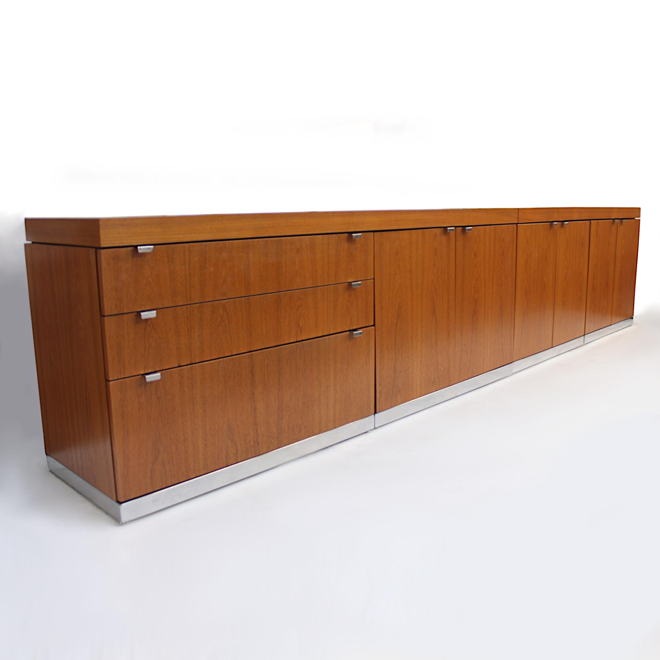 Massive teak credenza by John Geiger for IIL (later Herman Miller). Credenza features beautiful book-matched grain teak veneer, chrome pedestal bases, chrome hardware and a modular setup allowing it to be two separate pieces (5 & 6 feet) or one