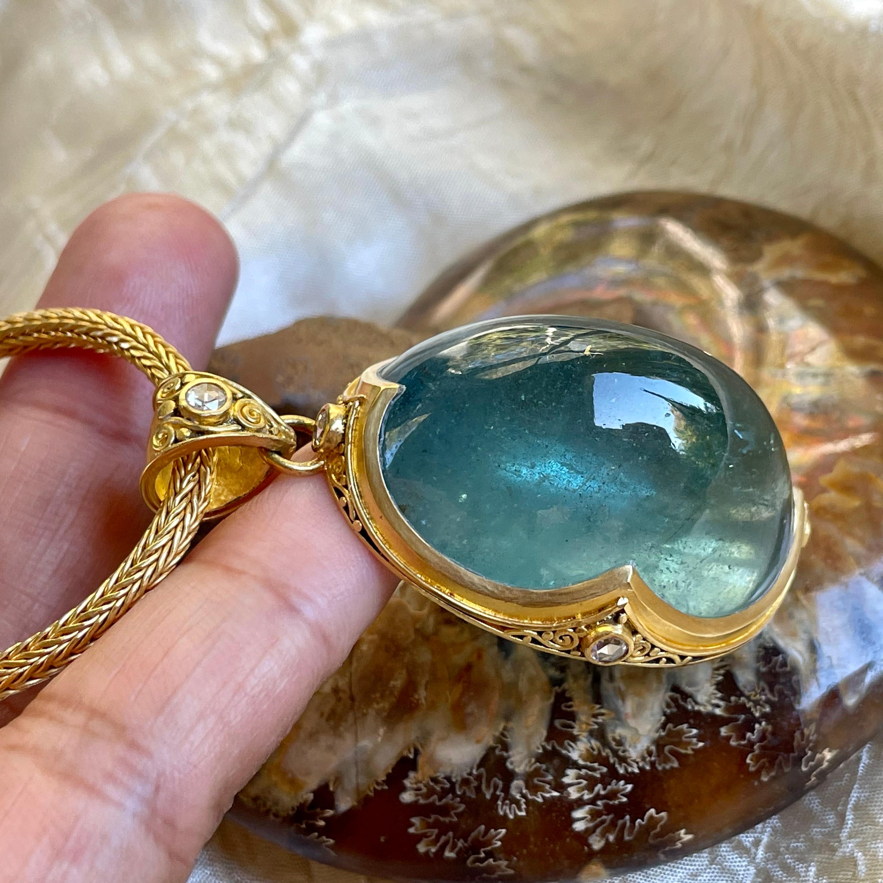 An incredible deep blue Brazilian aquamarine 27 x 36 mm oval cabochon is the centerpiece of this amazing handmade high-Karat gold pendant.  The stone is set in a Steven Battelle designed signature 
