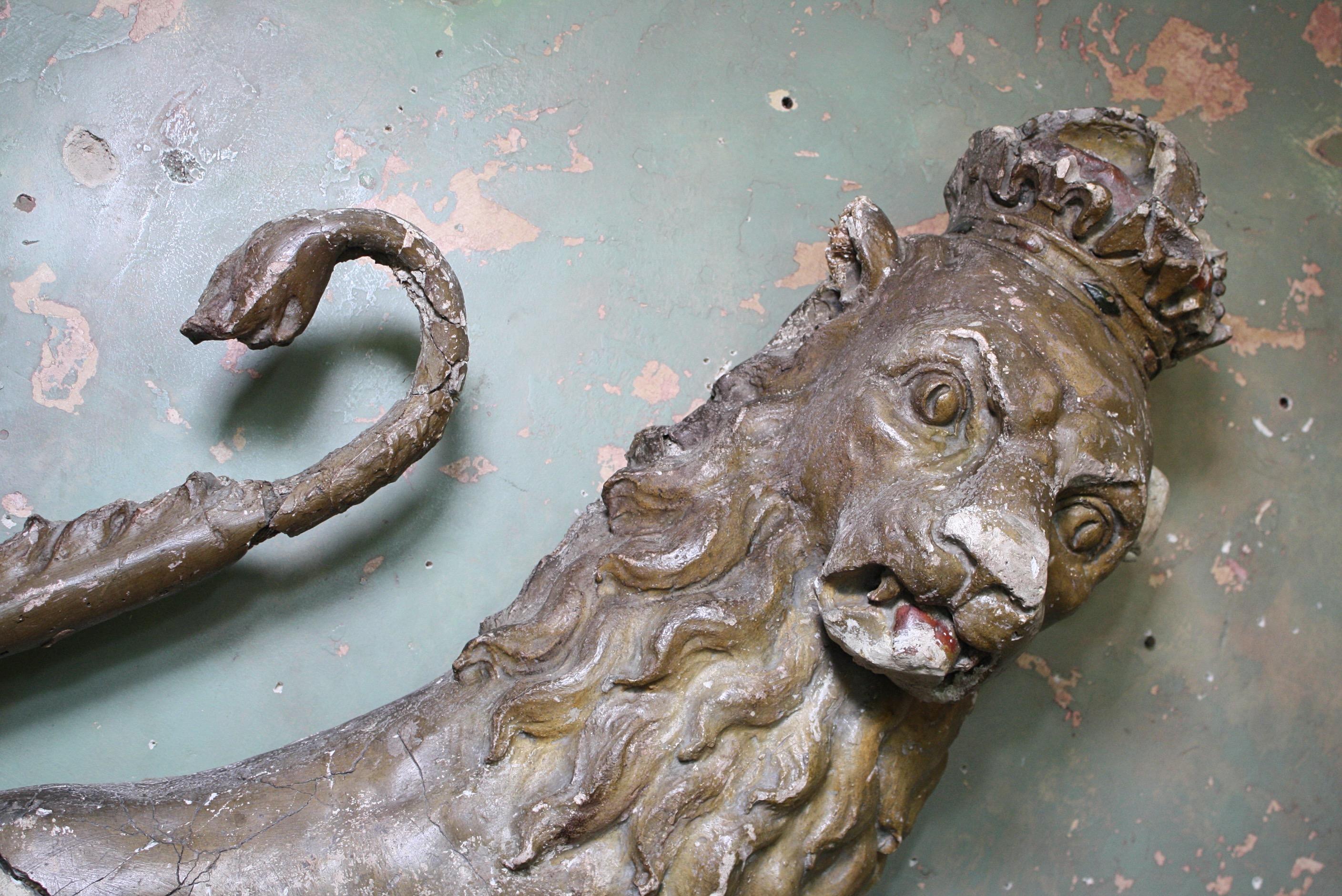 A large scale heraldic gilt lion off naive depiction, constructed around a pine carcass with a thick hessian and plaster/gesso skin.

The original gilt is beautifully faded, the plaster work had age related wear and cracking, the odd elderly