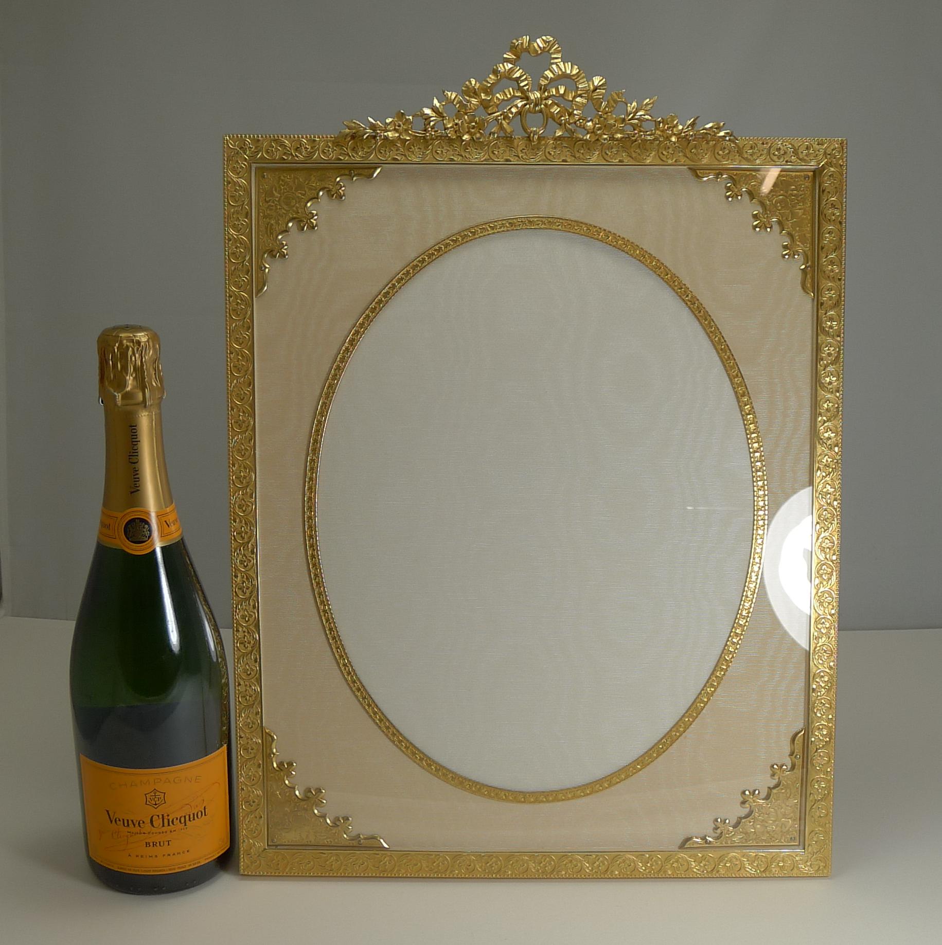 A magnificent and very grand photograph frame; if you are looking for a statement piece, this may very well be it.

Made from Ormolu or gilded bronze, it has been meticulously restored to it's former glory with a bright patina, clean silk taffeta
