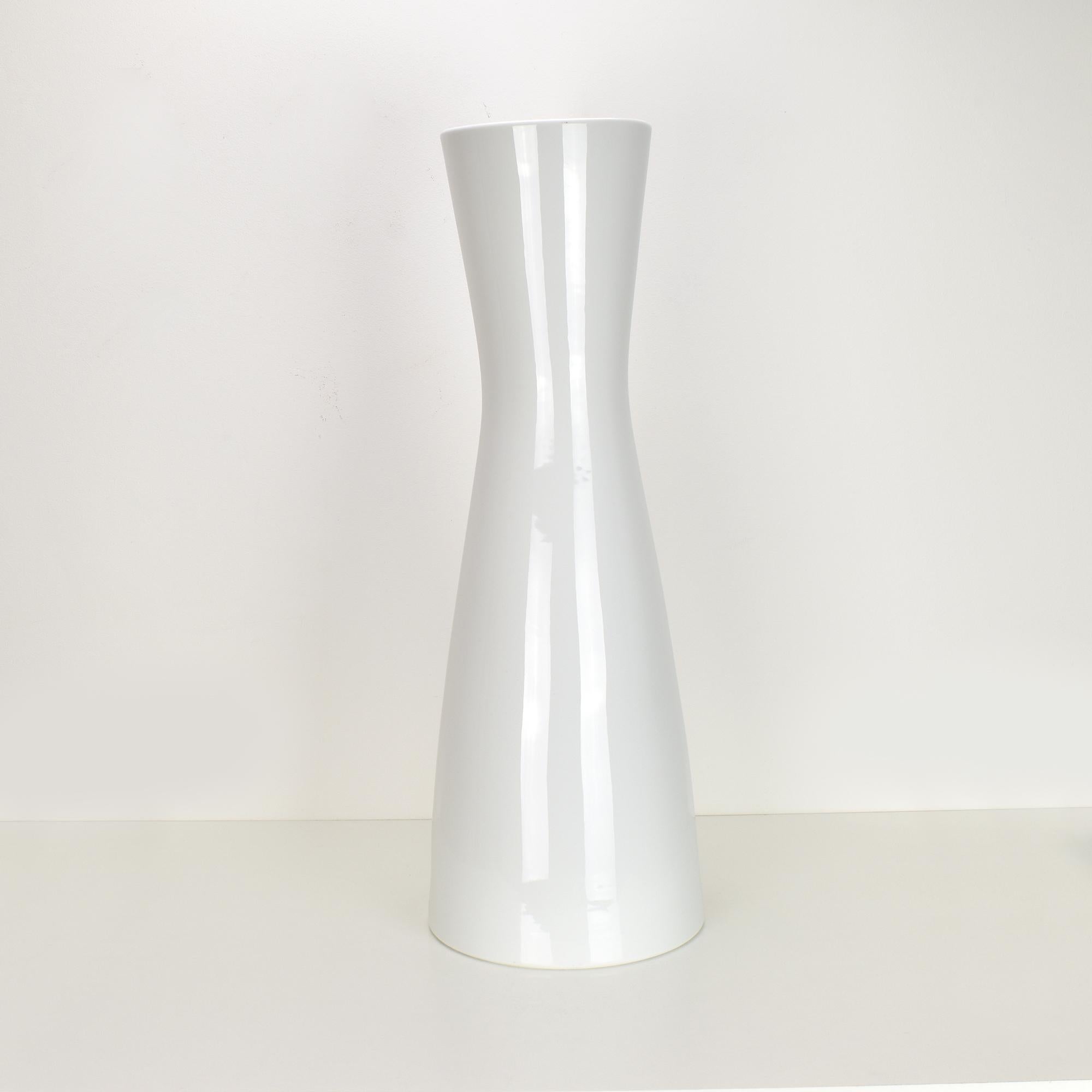 This elegant 1950s floor vase or umbrella stand, crafted by Rosenthal, features a distinctive diabolo shape in high-gloss white porcelain. The vase's minimalist design emphasizes clean lines and a sleek silhouette, making it a versatile piece