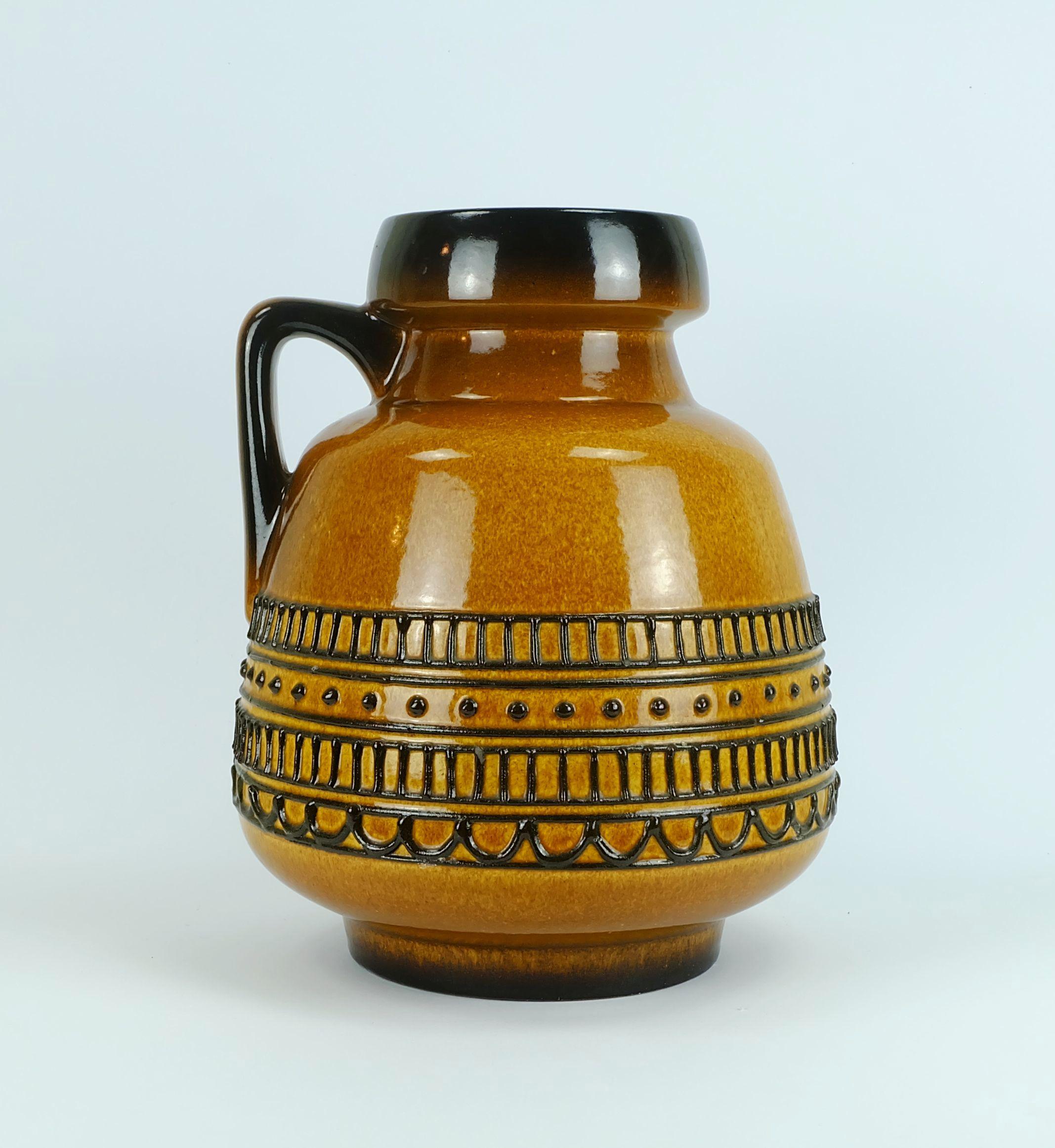 Énorme vase-pichet des années 1960 avec glaçure brillante ambre et brune et motif géométrique en relief en noir. Marqué au bas 88 35. 

Hauteur 13 3/4