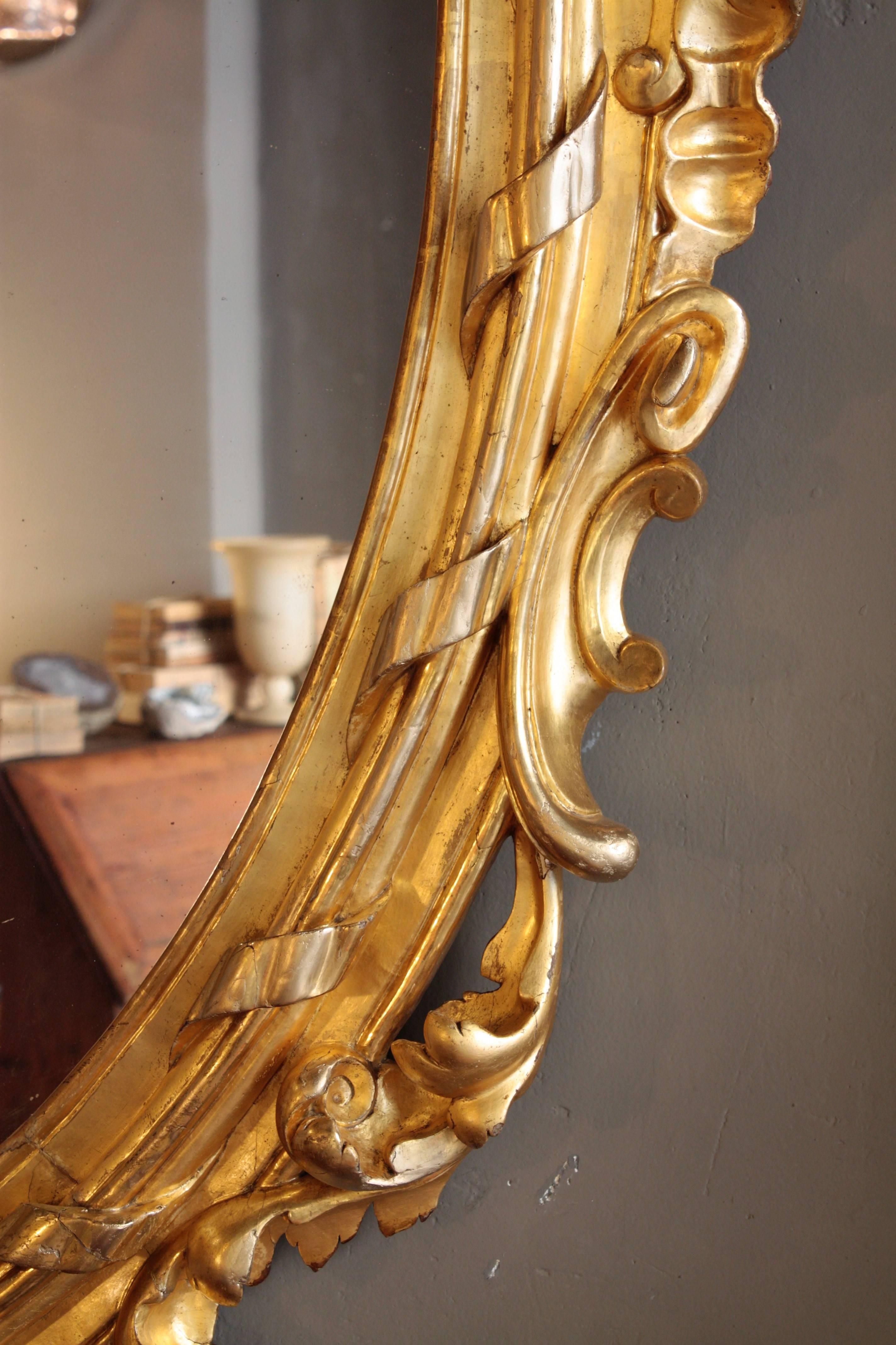 Français Miroir ovale palatial en bois doré sculpté de style rococo français en vente