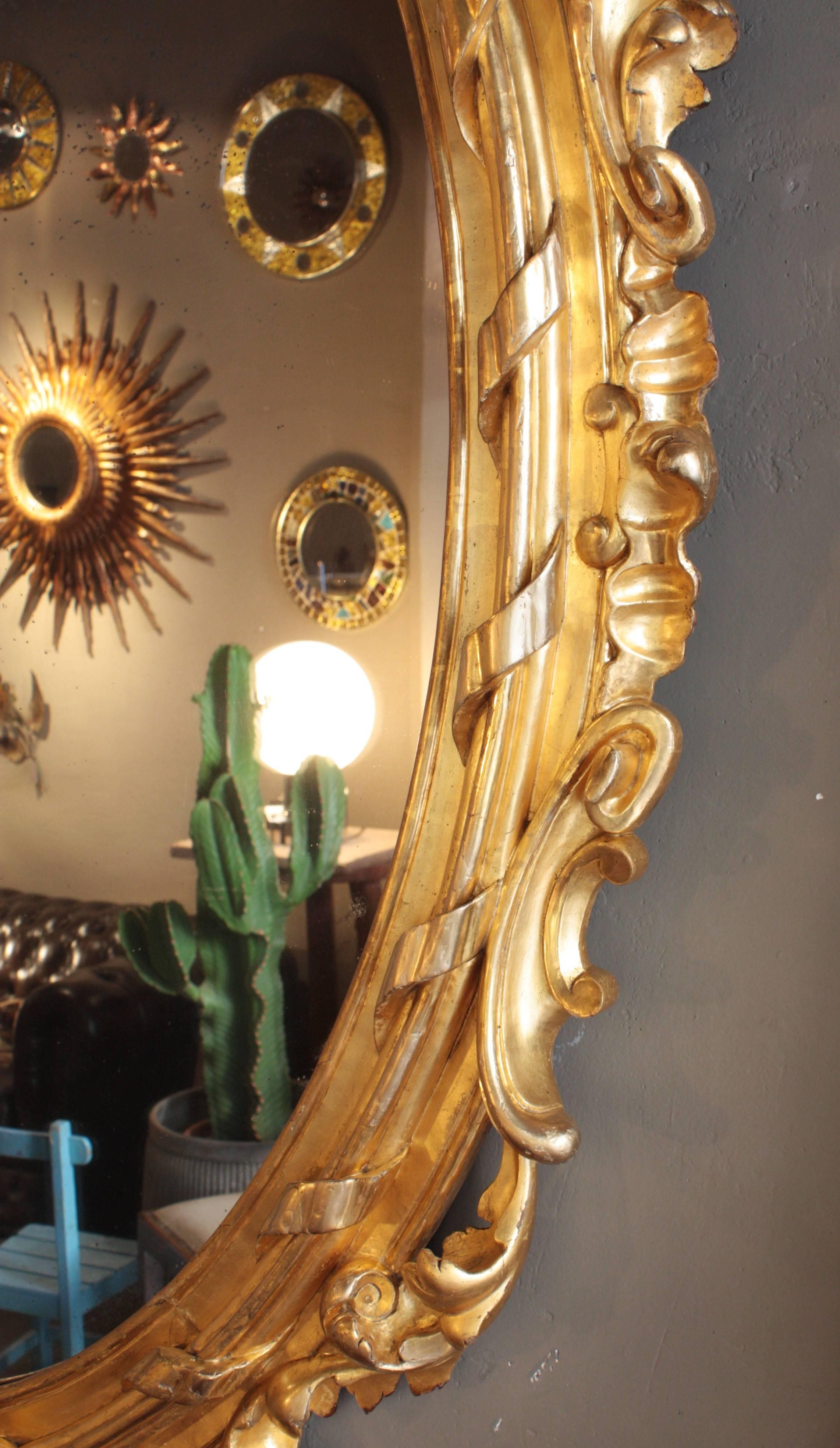 Bois doré Miroir ovale palatial en bois doré sculpté de style rococo français en vente