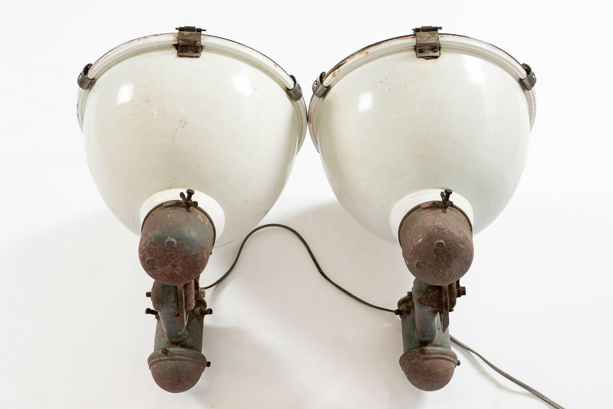Increíble par de lámparas industriales vintage de gran tamaño fabricadas por Westinghouse. Cubiertas originales cóncavas de cristal pesado que se abren y cierran Reflectores metálicos en los interiores. Herrajes pivotantes en la base. No