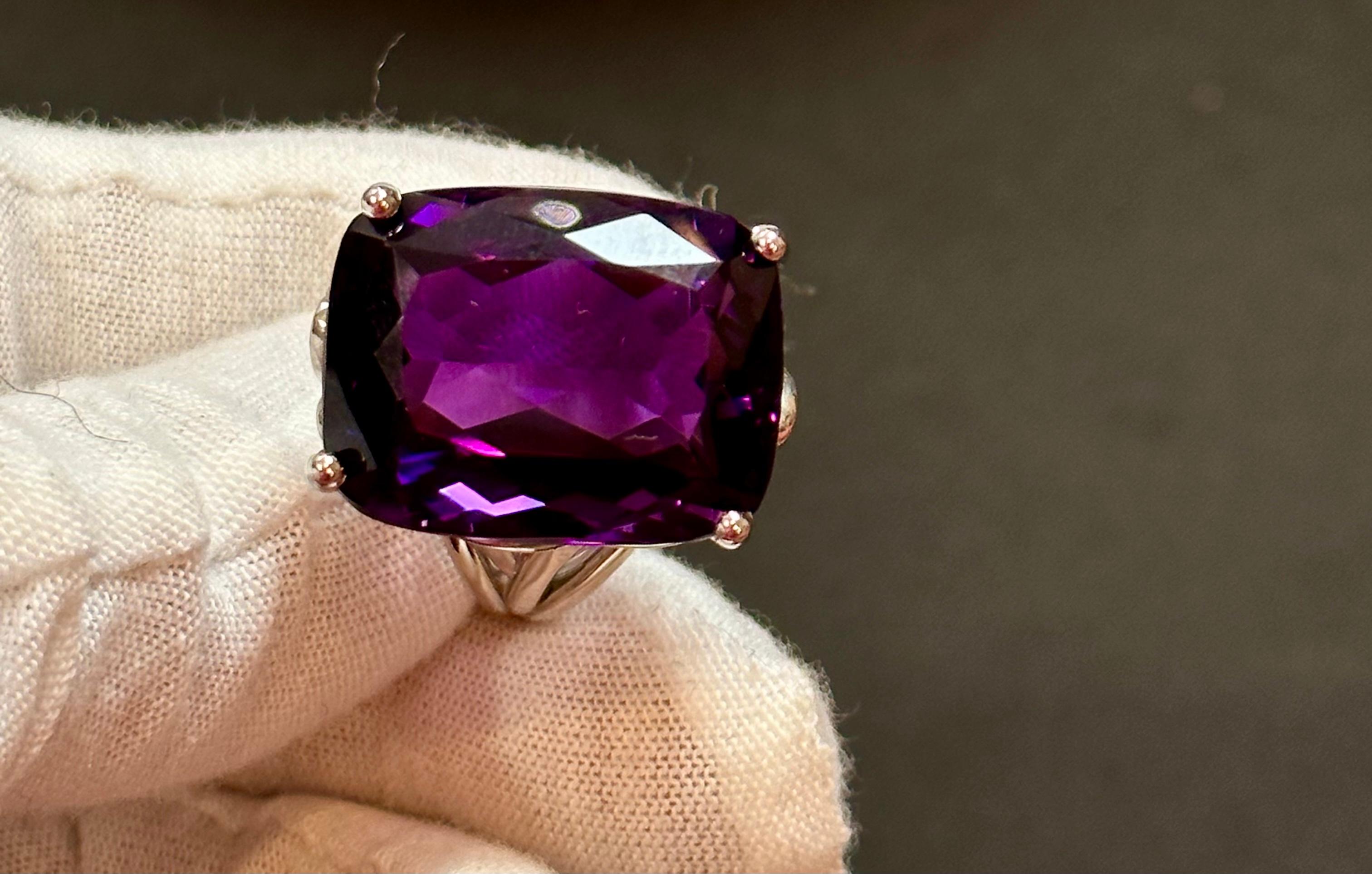  This vintage cocktail ring is a stunning piece of jewelry that features a huge 38 carat cushion-cut natural amethyst set in platinum. The amethyst measures 17 x 21 mm, giving the ring a substantial size and presence. The weight of the ring with the