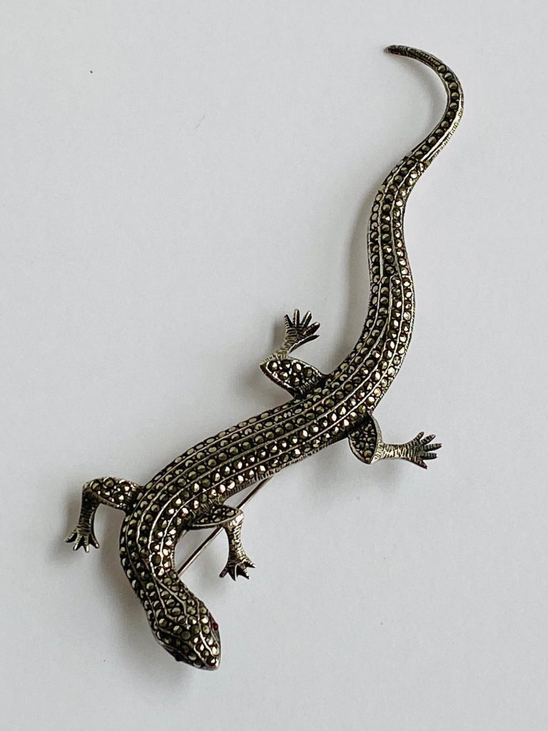 A stunning and statement making Art Deco style salamander pin in sterling silver and marcasite. The salamander is cast in sterling silver with an etched designer for texture along the edges. Additionally, it is hand set with over 250 cut marcasite