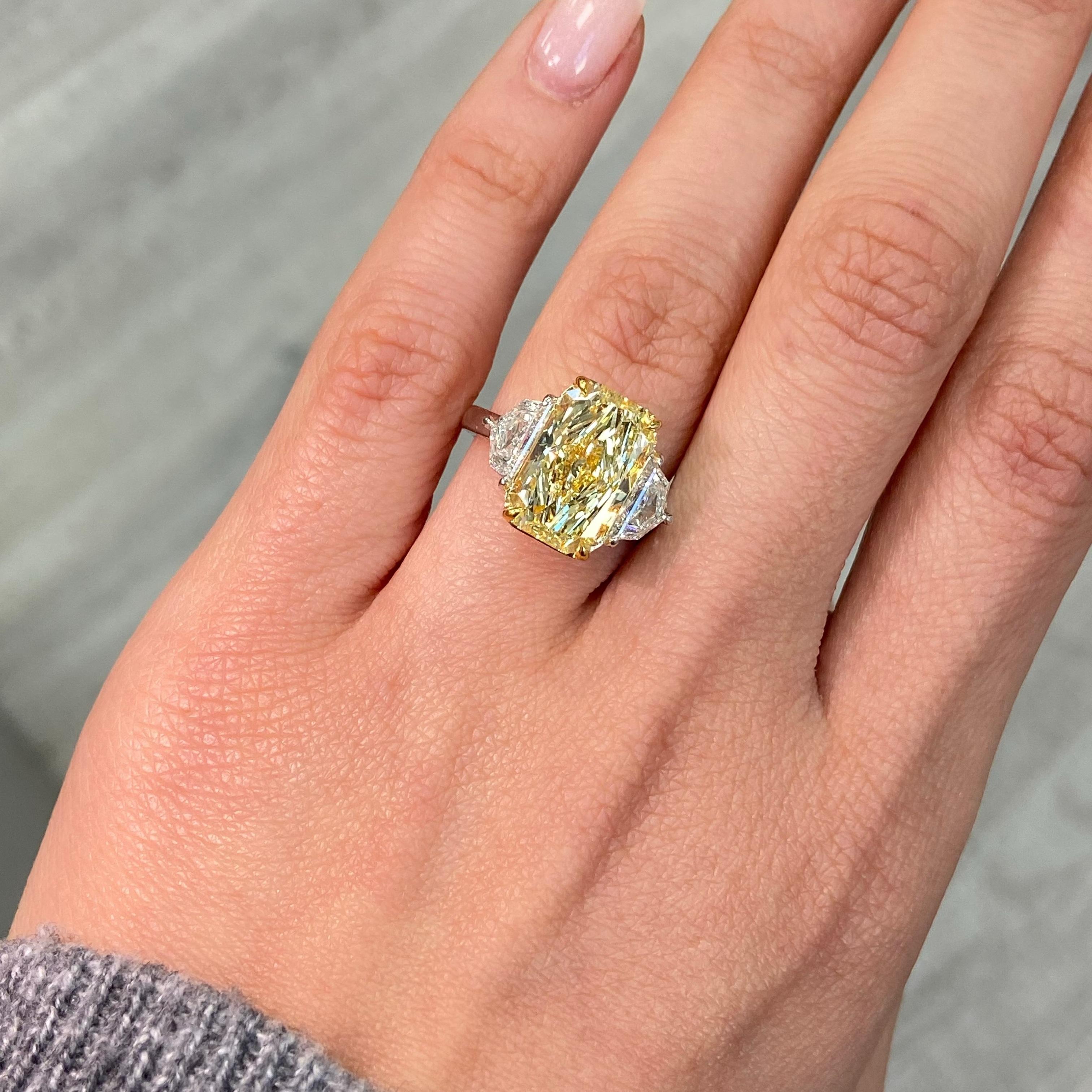 This breathtaking engagement ring showcases a 5.19 carat Fancy Yellow elongated radiant cut diamond, celebrated for its vibrant color and exceptional brilliance. GIA-certified with SI1 clarity and excellent cutting, this rare center diamond is a