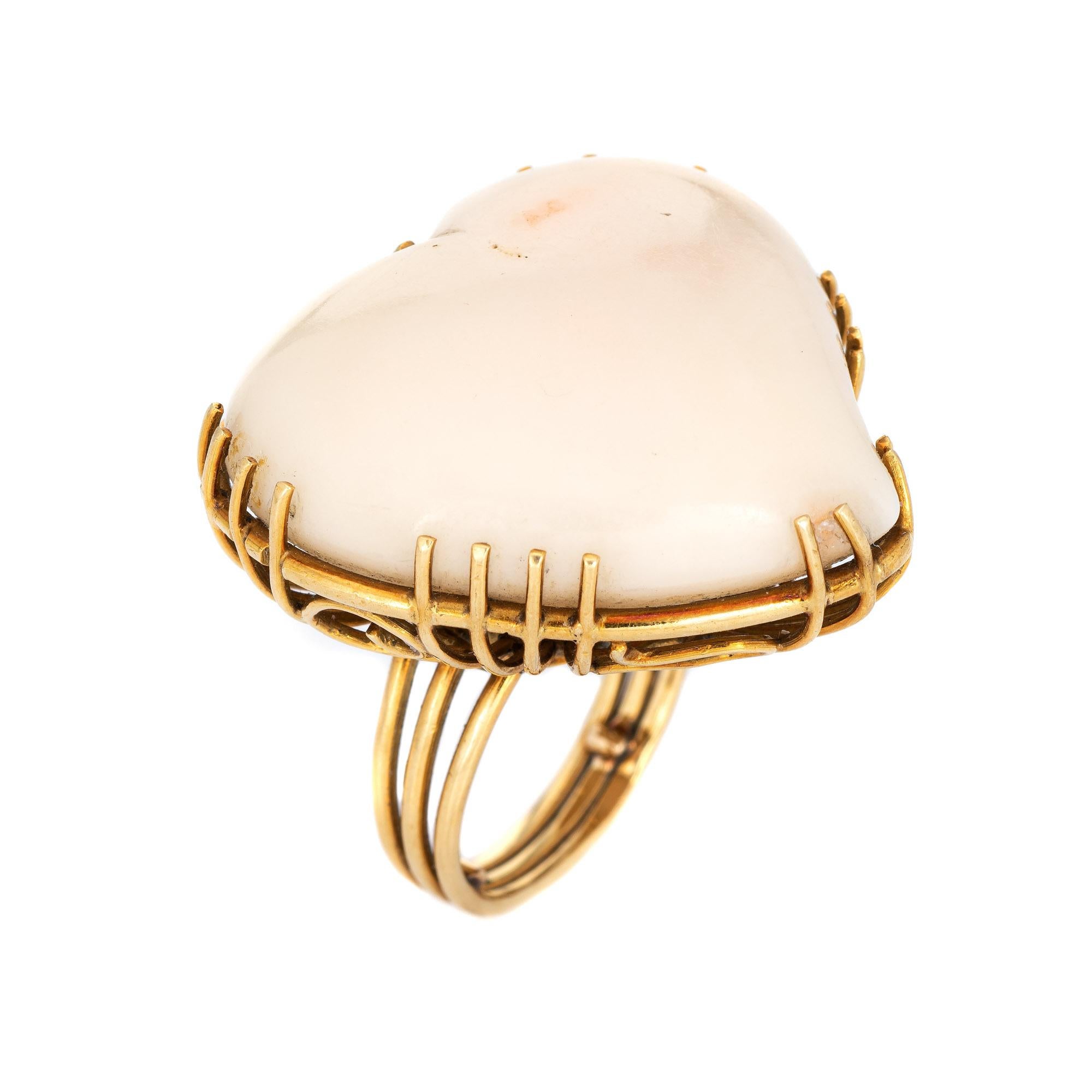 Stylish vintage huge angel skin coral heart cocktail ring (circa 1960s) crafted in 18 karat yellow gold. 

Angel skin coral cabochon measures 30mm x 29mm (estimated at 65 carats). The coral is in excellent condition and free of cracks or chips.