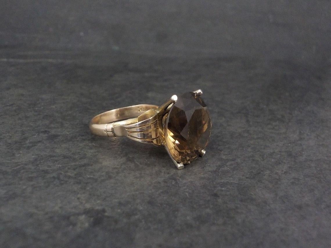 This huge, gorgeous ring is 14k yellow gold with a 15mm smoky quartz gemstone.

The face of this ring measures 5/8 of an inch north to south with a rise of 14mm off the finger.
Size: 7

Marks: 14K

Condition: Excellent