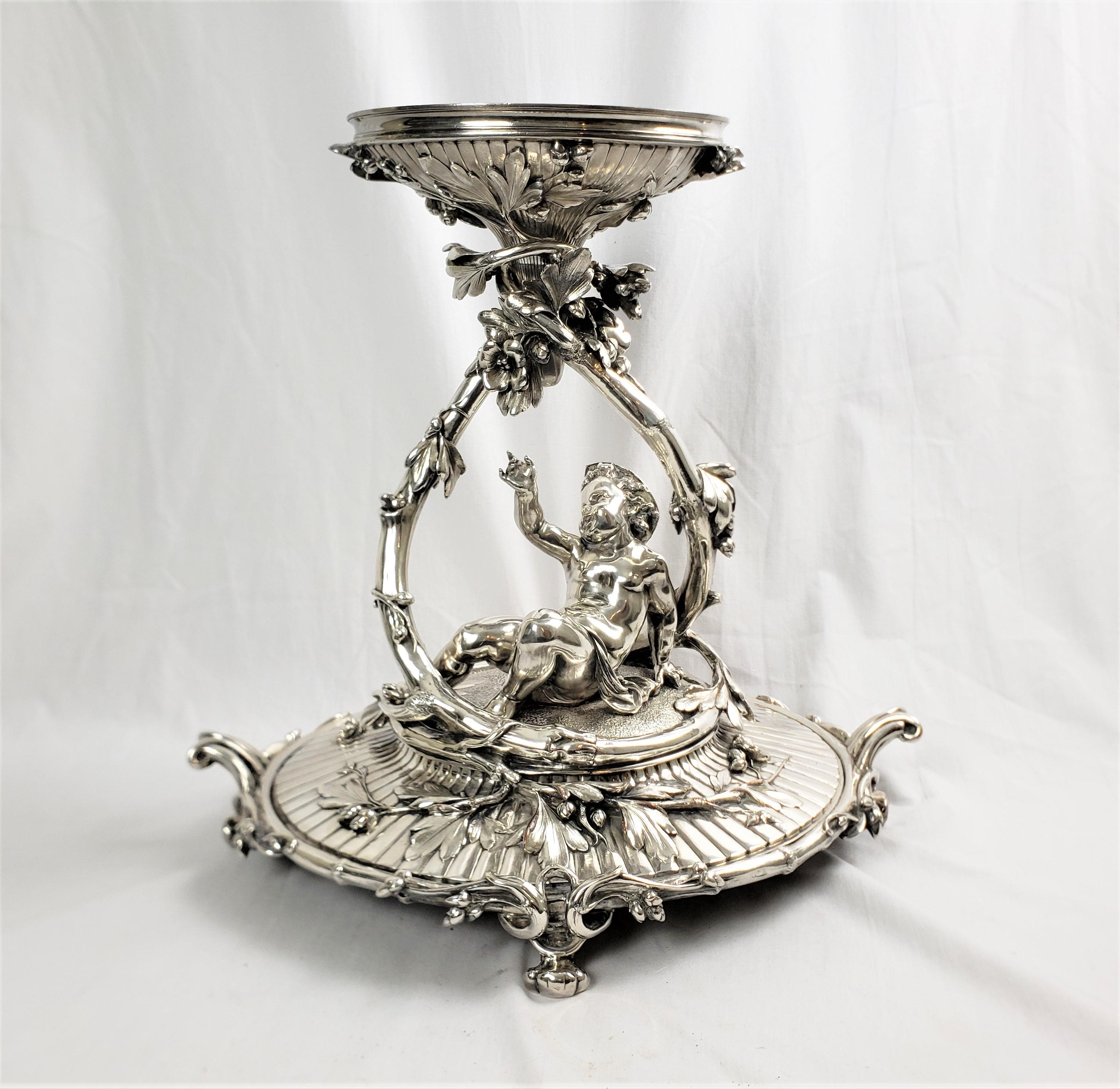This very large and substantial antique centerpiece was made by the well known Christofle company of France in approximately 1880 in the period Victorian style. The centerpiece is composed of silver plate over copper and depicts a young child