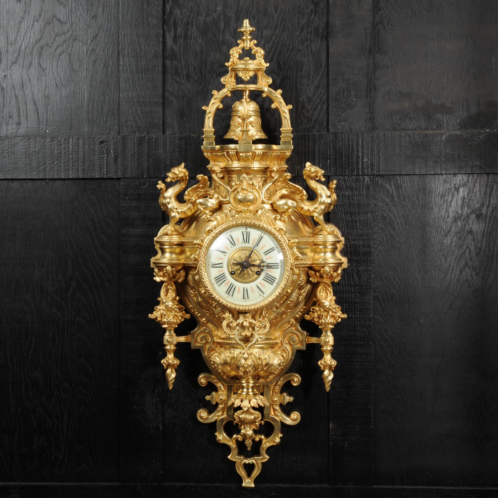 A magnificent gilded bronze cartel clock featuring two dragons standing guard above the clock, circa 1870. It is baroque in style with mythical creatures, stylised foliage and a bell hung from an arch to the top. It is almost 32 inches in height and