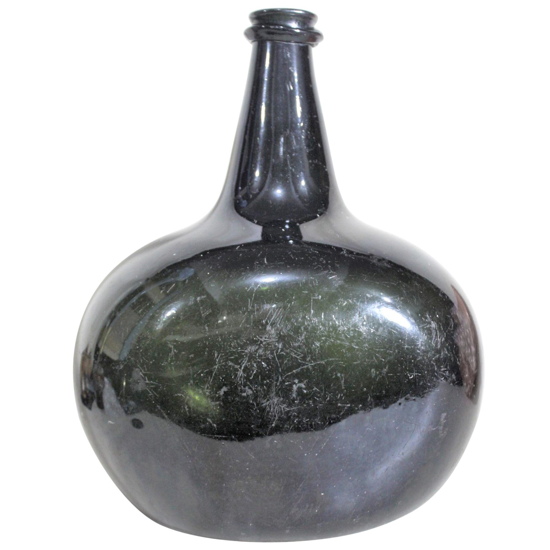 Große antike mundgeblasene und geformte dicke tiefgrüne Wein- oder Spirituosenflasche in Tiefgrün