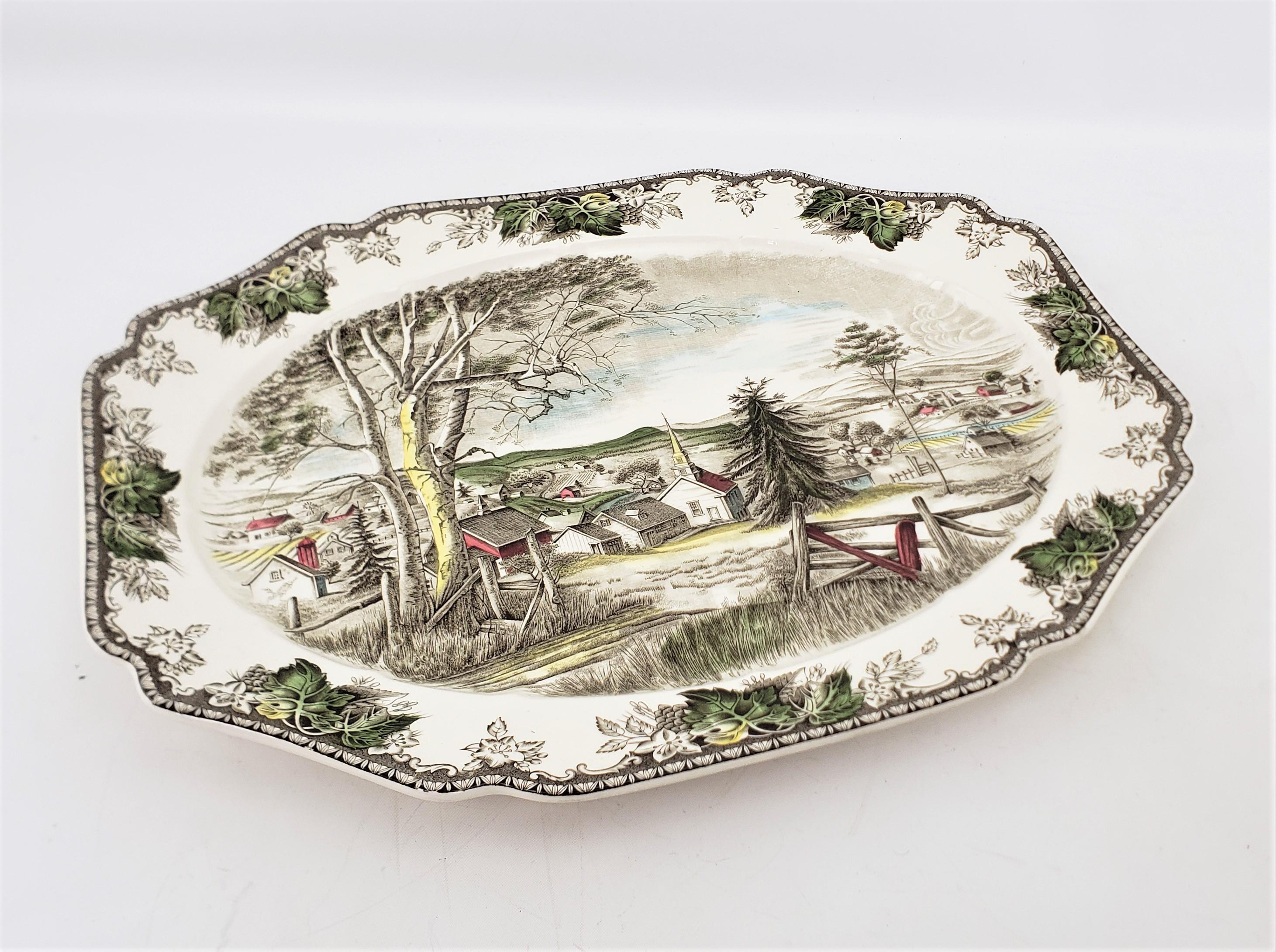 This extremely large serving platter was made by the well known Johnson Brothers of England in approximately 1920 in a Victorian style. The platter is ceramic with a cream ground and decorated with a central hand-engraving of a rural country