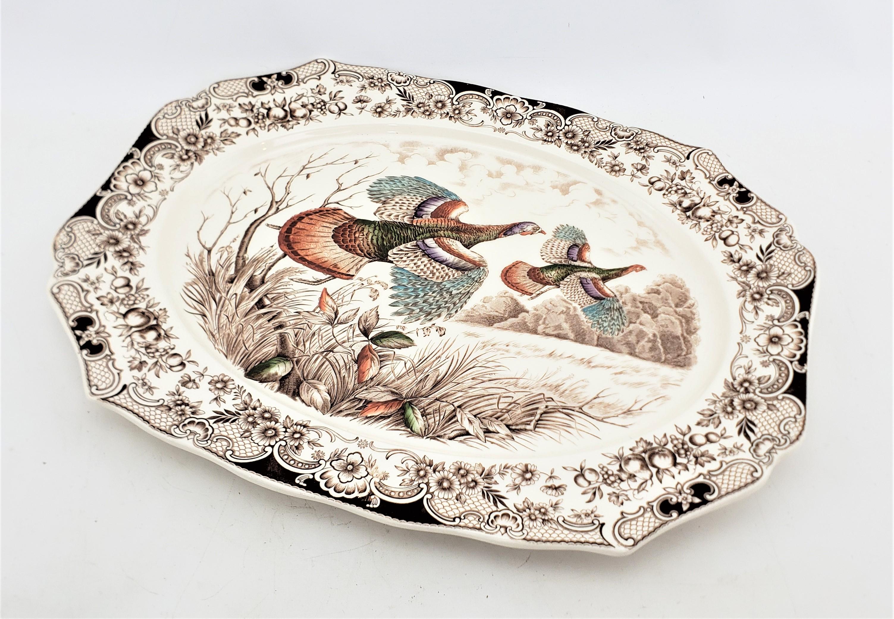 This extremely large serving platter was made by the well known Johnson Brothers of England in approximately 1900 in a period Victorian style. The platter is ceramic and comes from their Windsor Ware line, with a cream ground and decorated with a