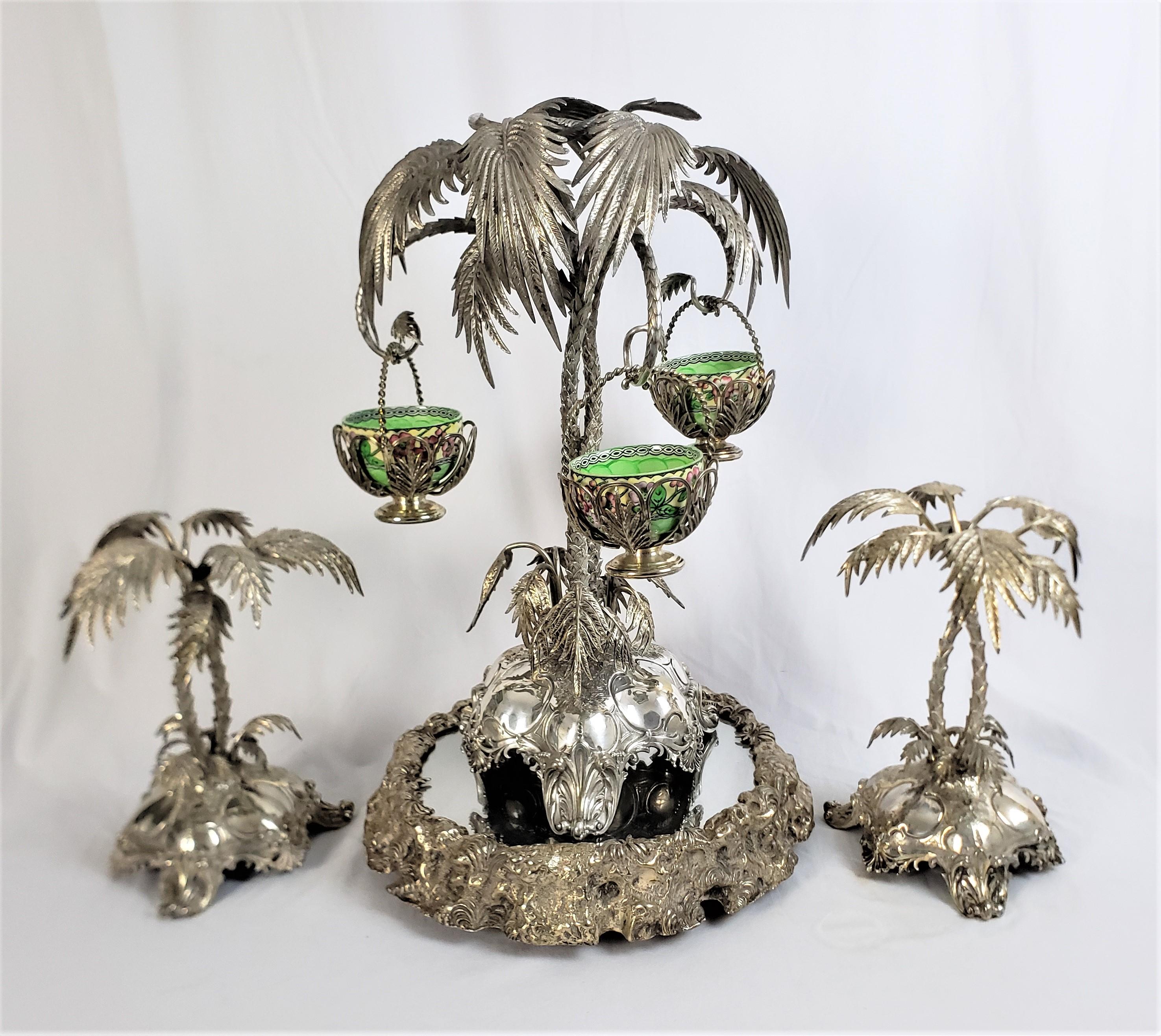 This very large and substantial centerpiece or serving set is hallmarked by an unknown maker, but originated from Scotland and dates to approximately 1890 and done in an Anglo-Indian style. This very elaborate and ornately cast set is done in silver