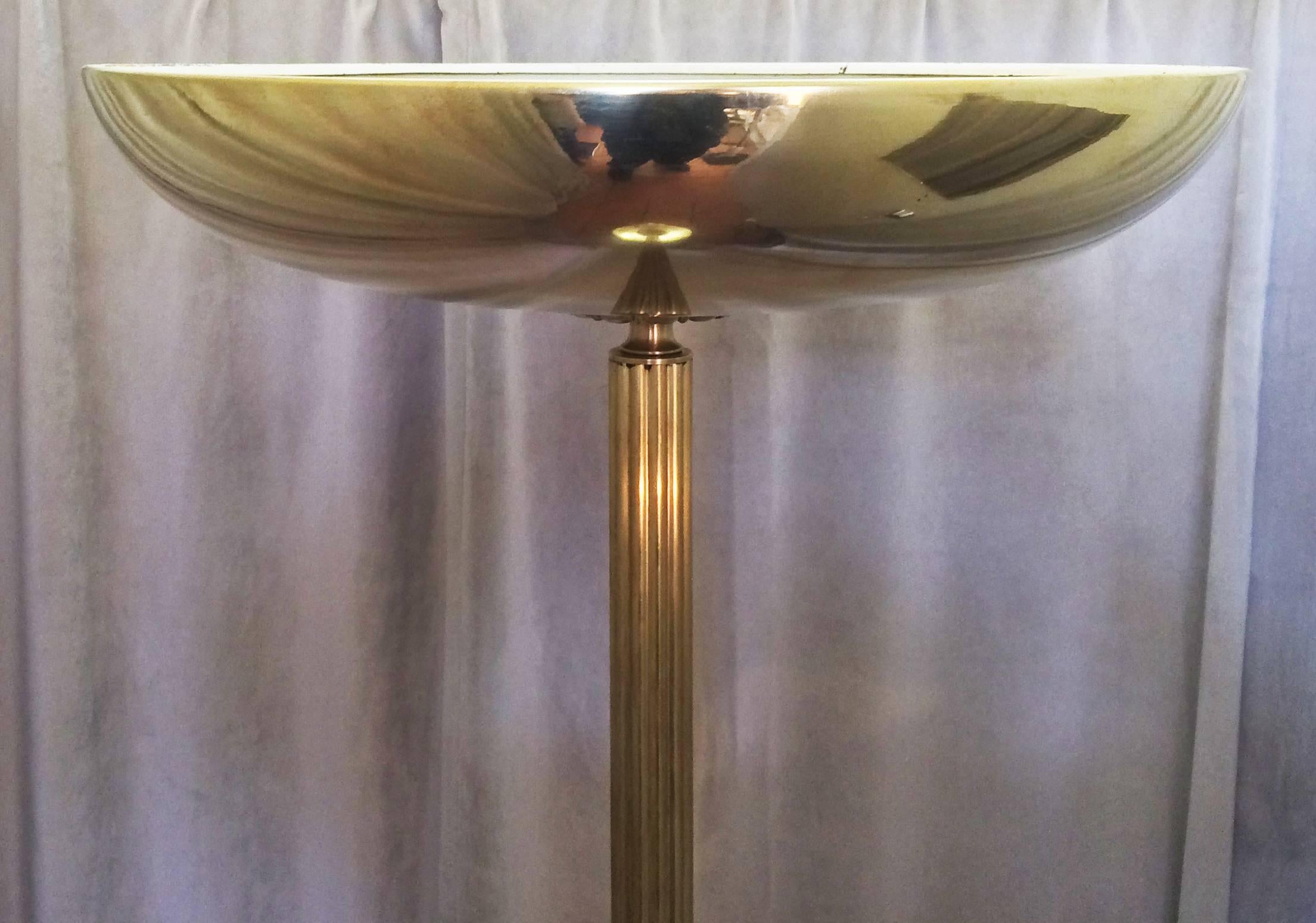 Art Deco bronze torchiere / uplighter standard lamp, with reeded vertical column and solid cast decorative bronze supports at top and bottom; the top is an upward semi dome, and the base is rounded edge large disc for stability. The lamp is in