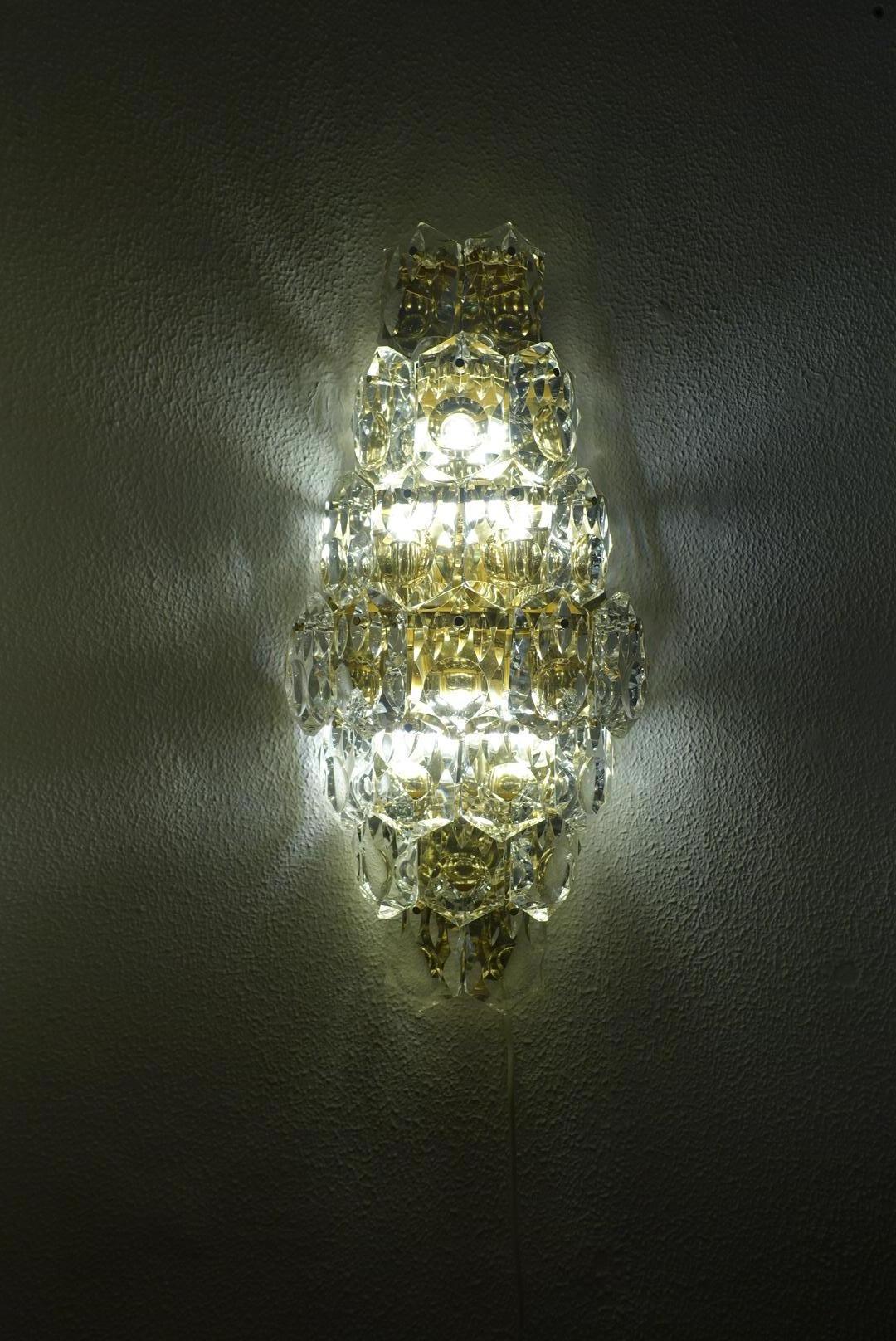 Stunning Huge golden sconce with crystal glasses, made by Kinkeldey, Germany, circa 1970-1979. It’s composed of crystal glass pieces on a gilded brass frame.

A luxurious gold-plated frame and thick diamond crystal sconce by the famed maker,