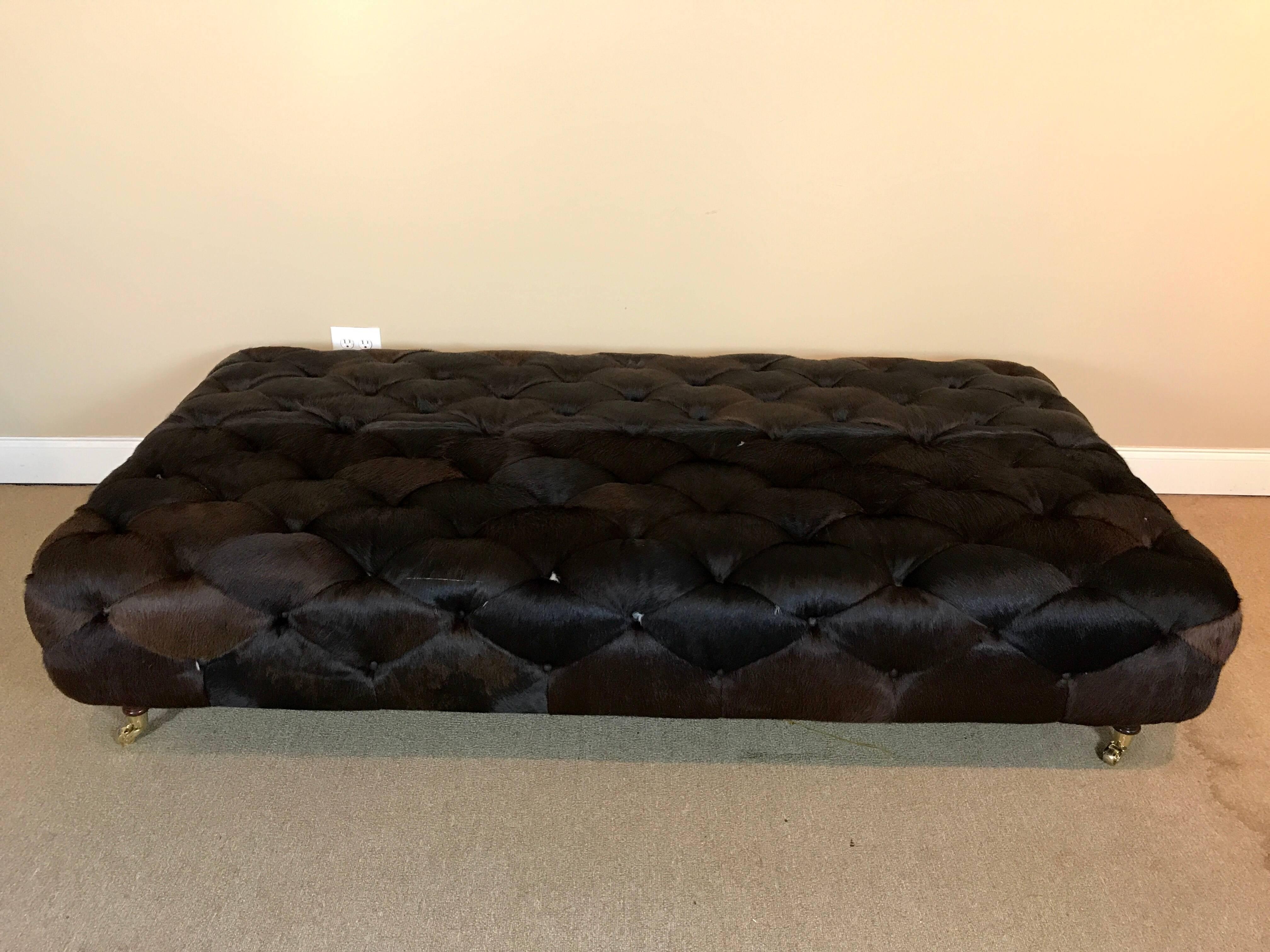 Huge custom cowhide ottoman/ coffee table, raised on four brass castor turned legs. Can even be used as a daybed.