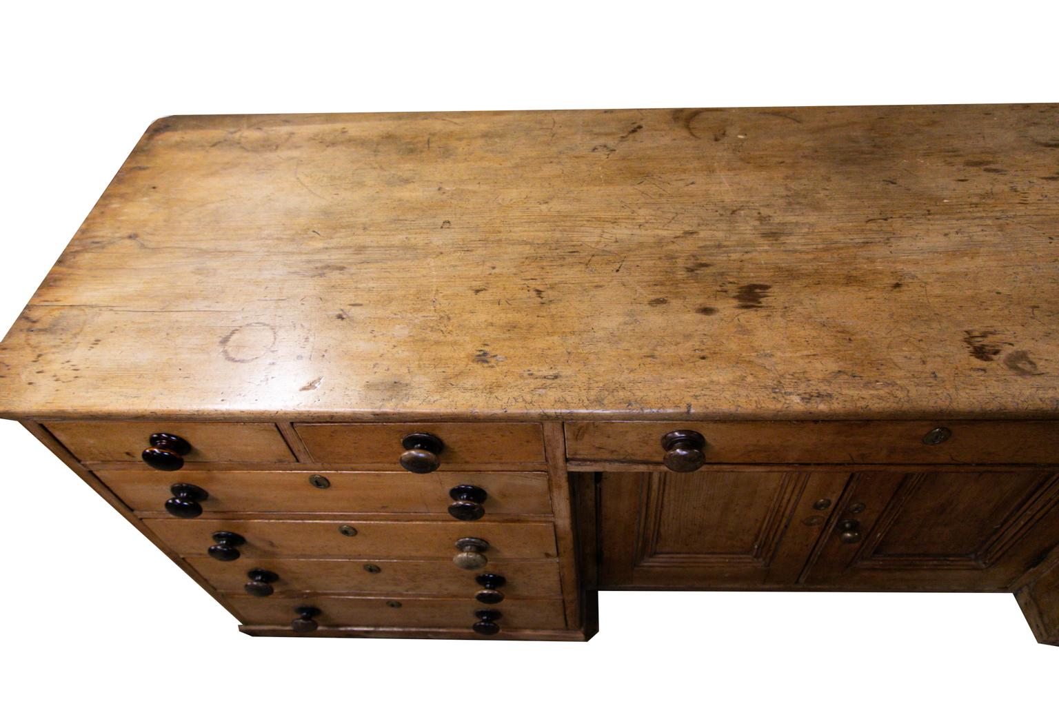 Huge English pine sideboard has three drawers and two doors. The painted knobs and turn latches are original. The top, with a bull nose edge, has a single board that is over two feet wide with a 2 1/2’ extension which is original. The sides have