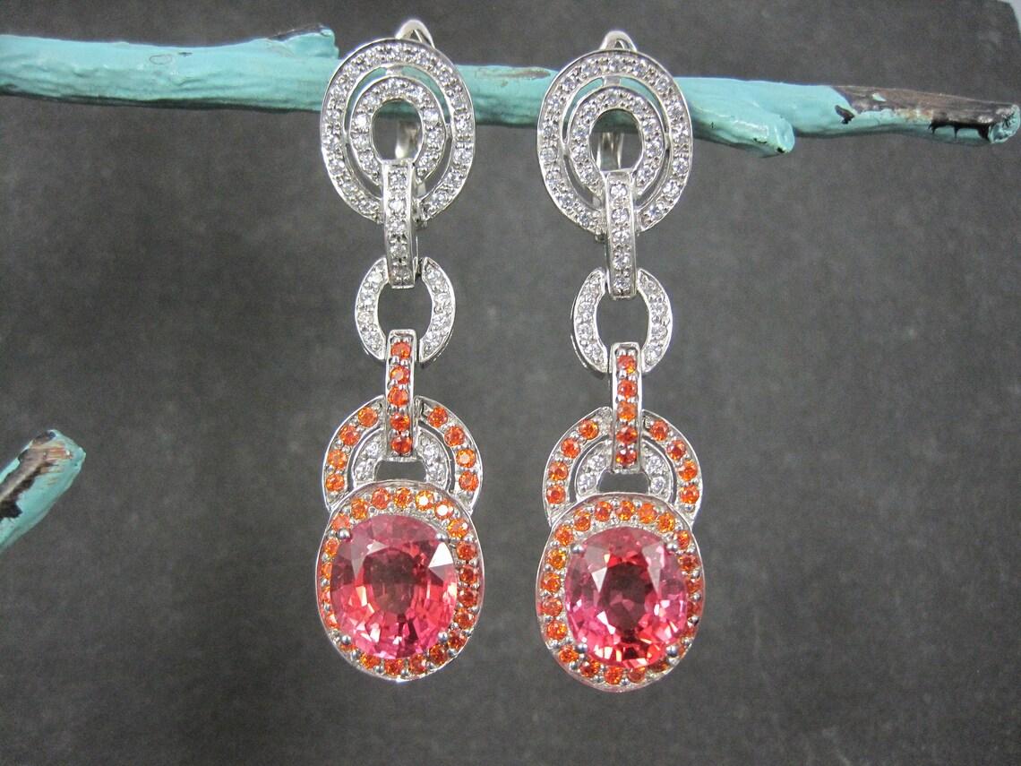 These gorgeous, custom latch-back earrings are sterling silver.
They feature stunning 11 by 12.5mm synthetic pink sapphires accented by orange and clear cubic zirconias.

Measurements: 5/8 by 2 3/8 inches
Weight: 18.9 grams

Marks: 925

New old