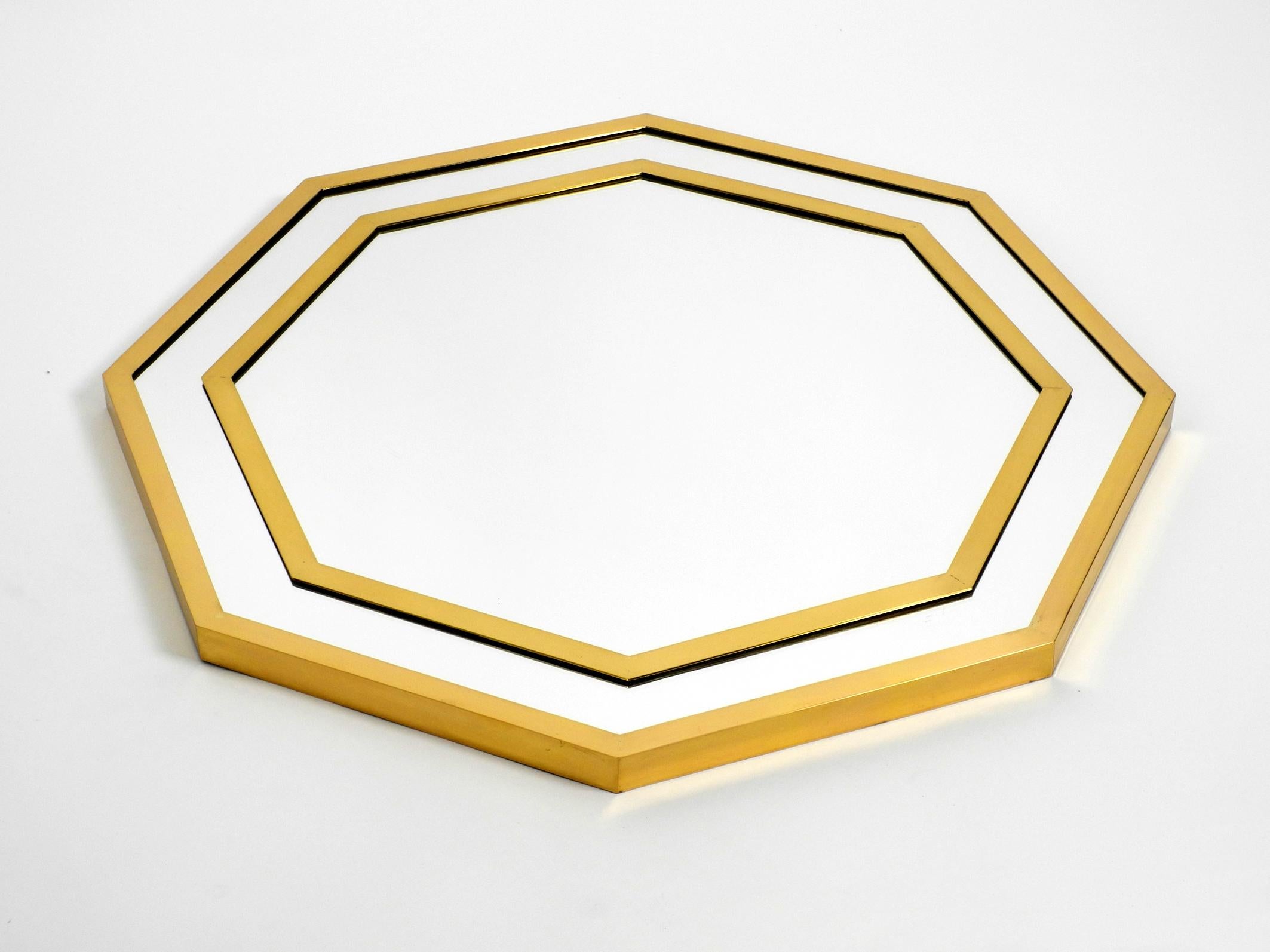 Huge fancy 1970s octagonal brass wall mirror from Vereinigte Werkstätten.
Great high quality design with two frames made of heavy brass. Typical 1970s Regency design.
Very good condition with no damages to the glass or frame.
There is one very