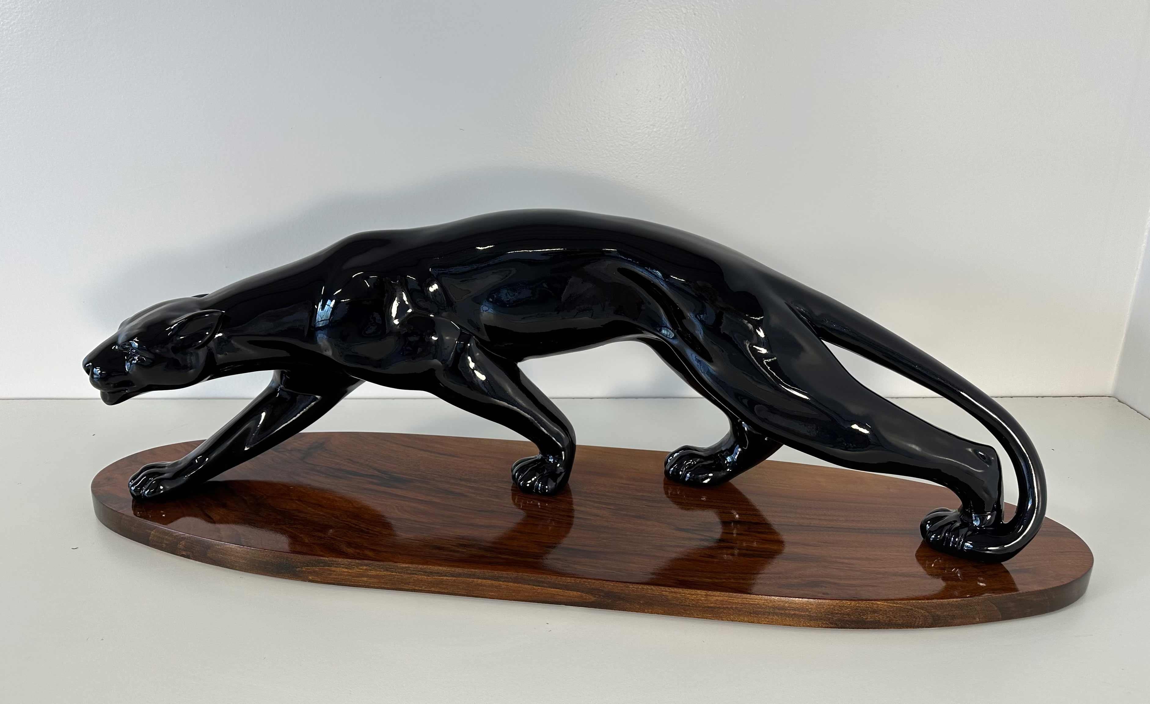 This huge Art Deco panther sculpture was produced in Paris, France in the 1930s.  
It is completely made of ceramic effect black lacquered plaster (gypsum) and lays on a walnut wood base. 

Attributable to Salvatore Melani. 

