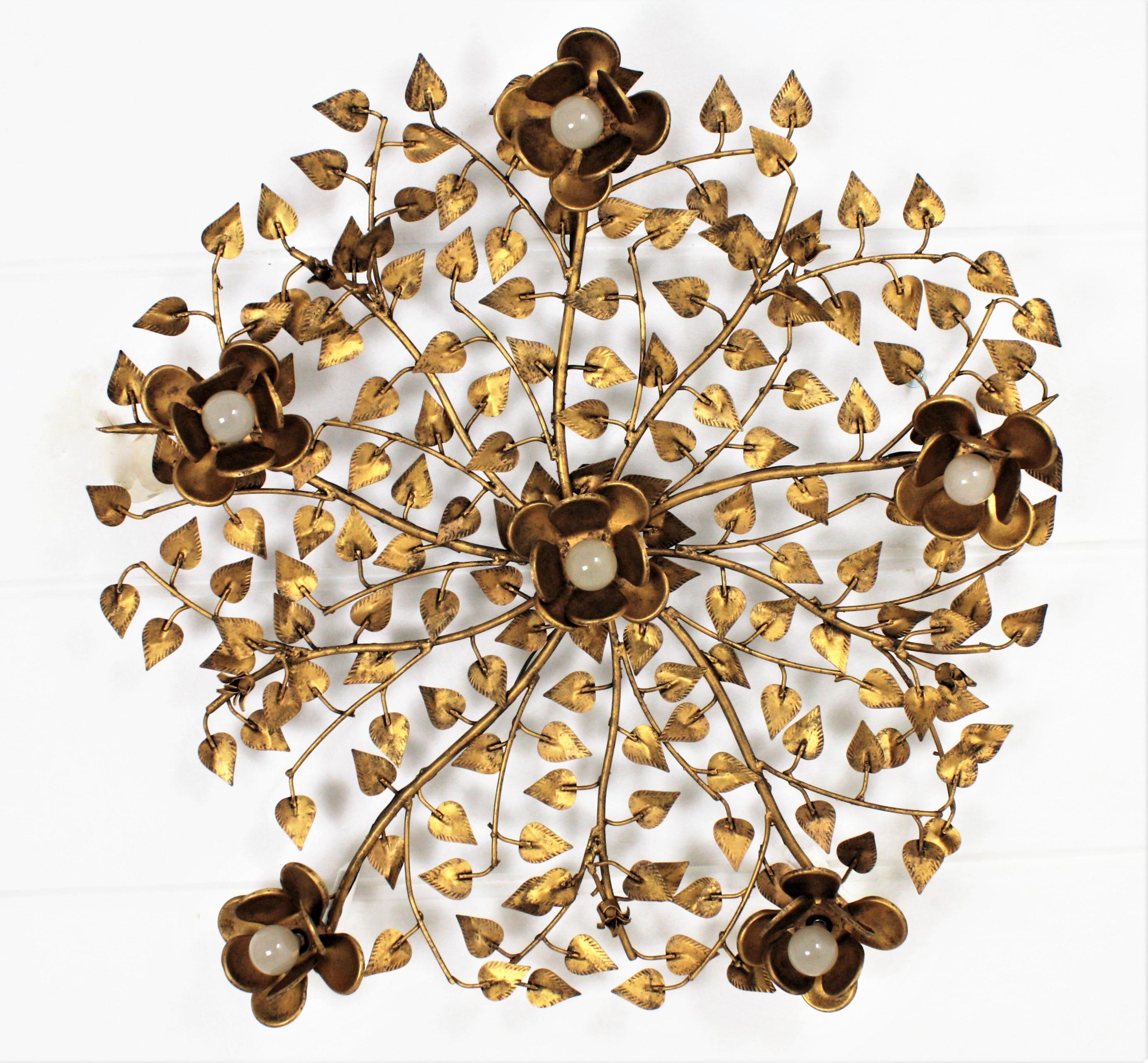 Outstanding large size hand-hammered gilt iron foliate flower bush ceiling light fixture with five flower lights. Spain, 1960s.
This ceiling light fixture was entirely made by hand. It features an intrincate of branches and leaves accented by 5