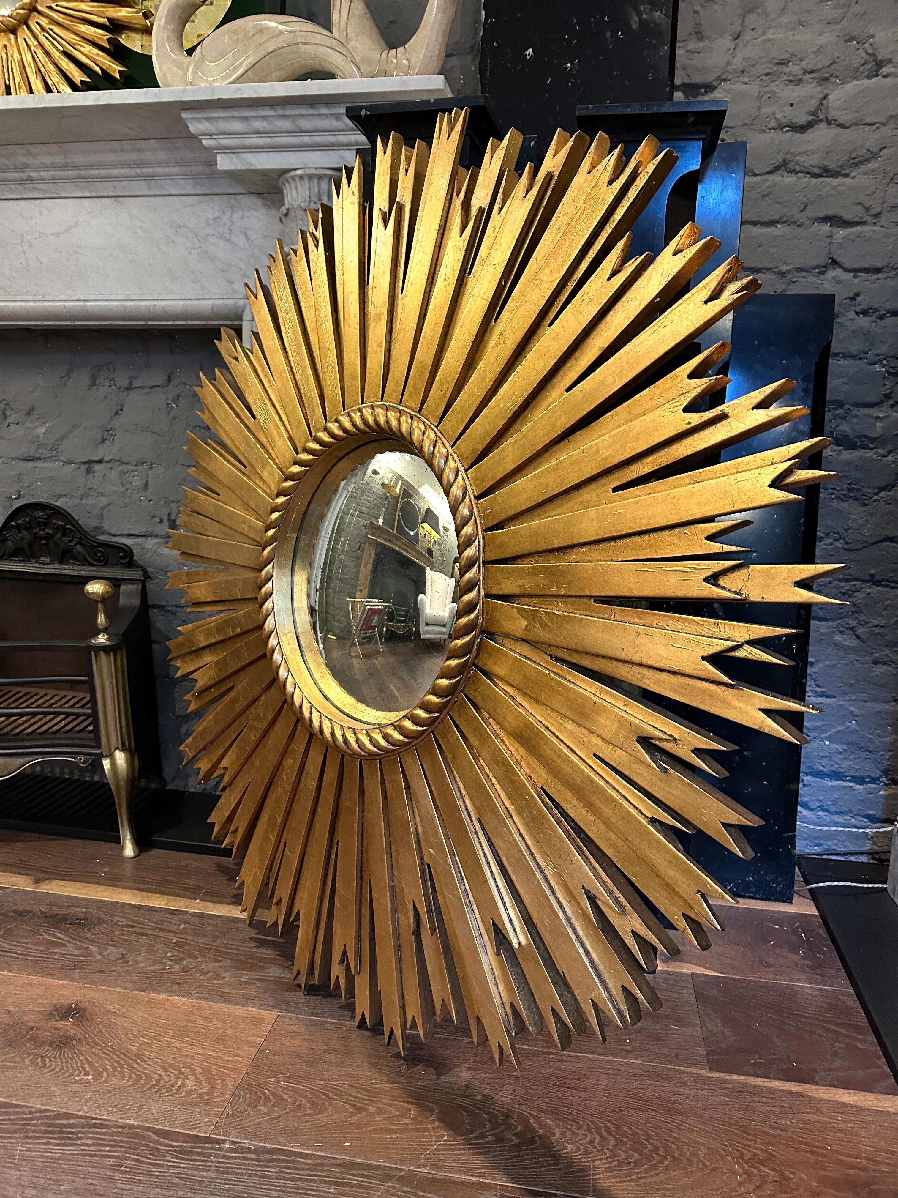 An Unusually large Gold Gilt sunburst mirror, carved from wood with a 40cm diameter distressed convex silver mirror in the centre framed with a gilt rope twist slip. Very good quality piece in the South of France taste.