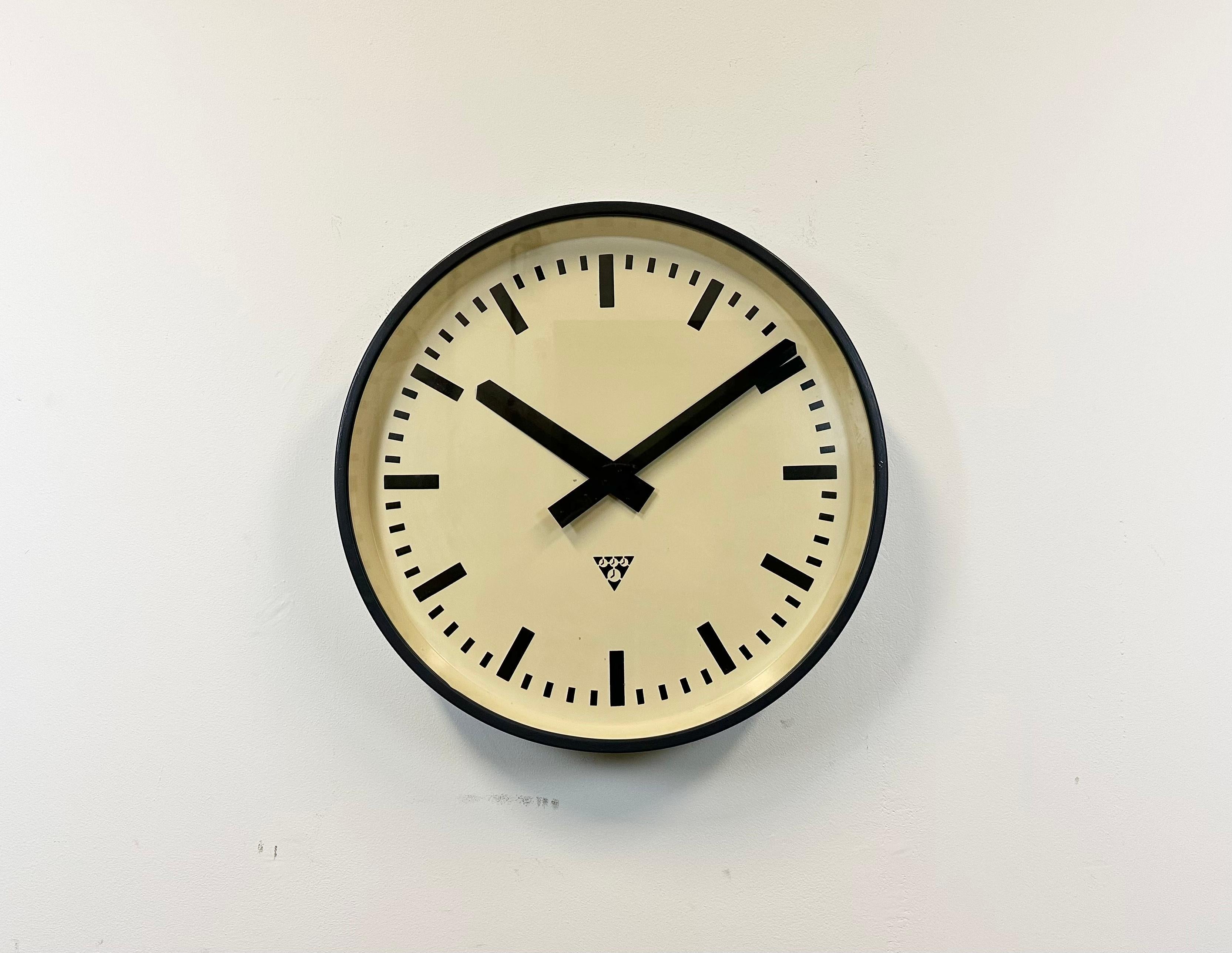 This wall clock was produced by Pragotron in former Czechoslovakia during the 1960s. It features a dark grey metal frame, an iron dial, an aluminium hands and a clear glass cover. The piece has been converted into a battery-powered clockwork and