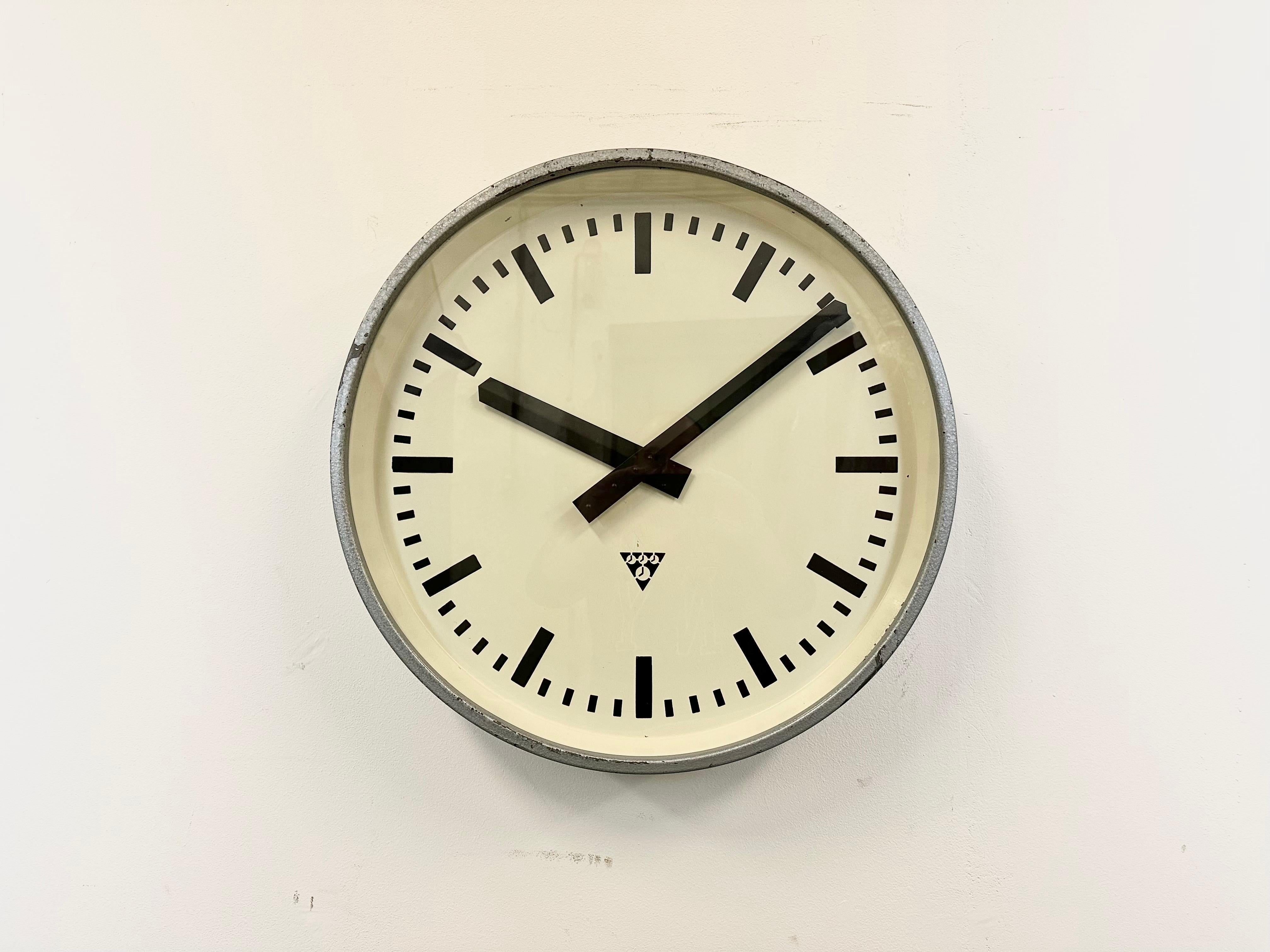 This wall clock was produced by Pragotron in former Czechoslovakia during the 1960s. It features a grey hammer paint metal frame, an iron dial, an aluminium hands and a clear glass cover. The piece has been converted into a battery-powered clockwork