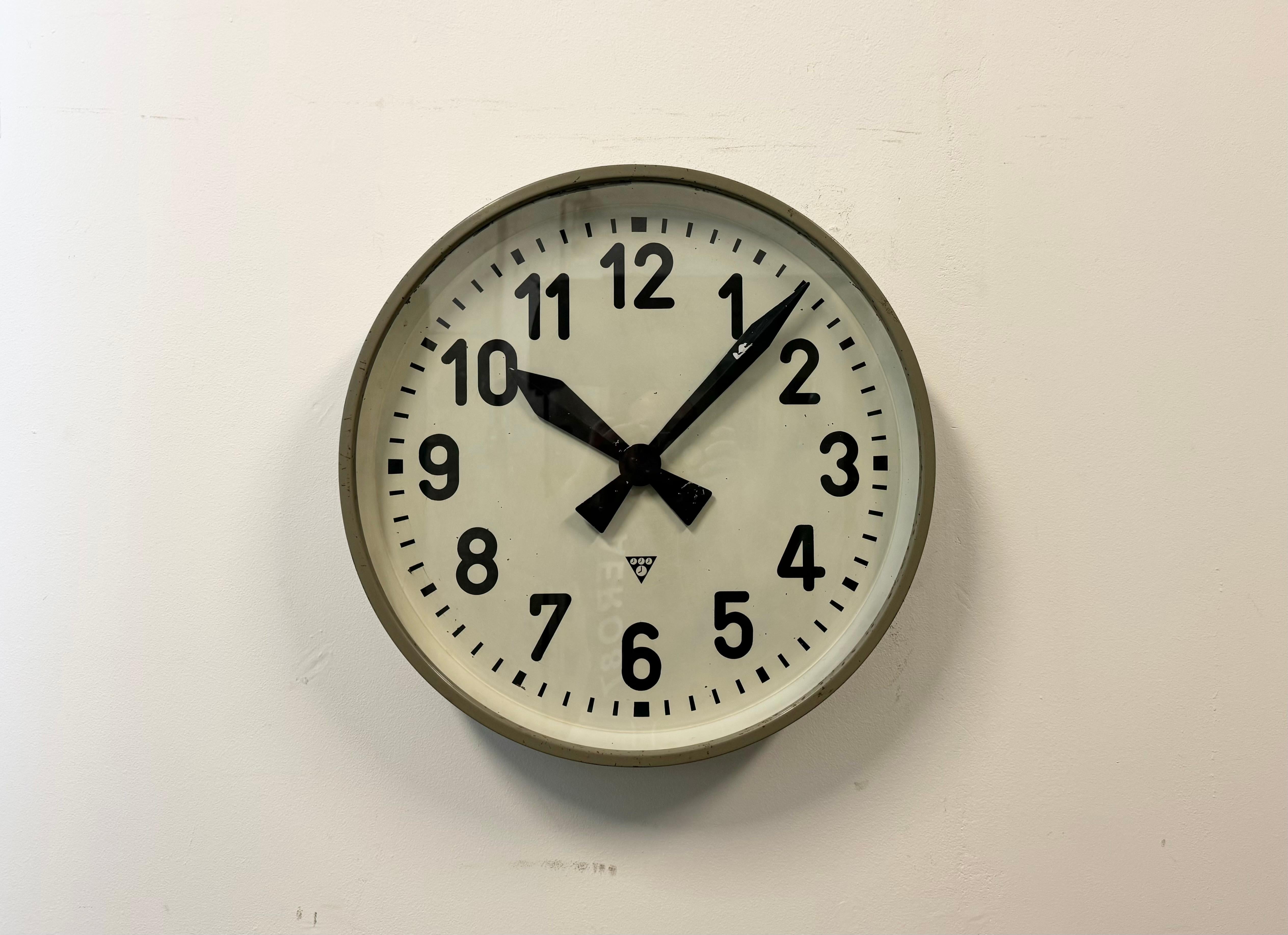 This wall clock was produced by Pragotron in former Czechoslovakia during the 1960s. It features a grey metal frame, an iron dial, an aluminium hands and a clear glass cover. The piece has been converted into a battery-powered clockwork and requires