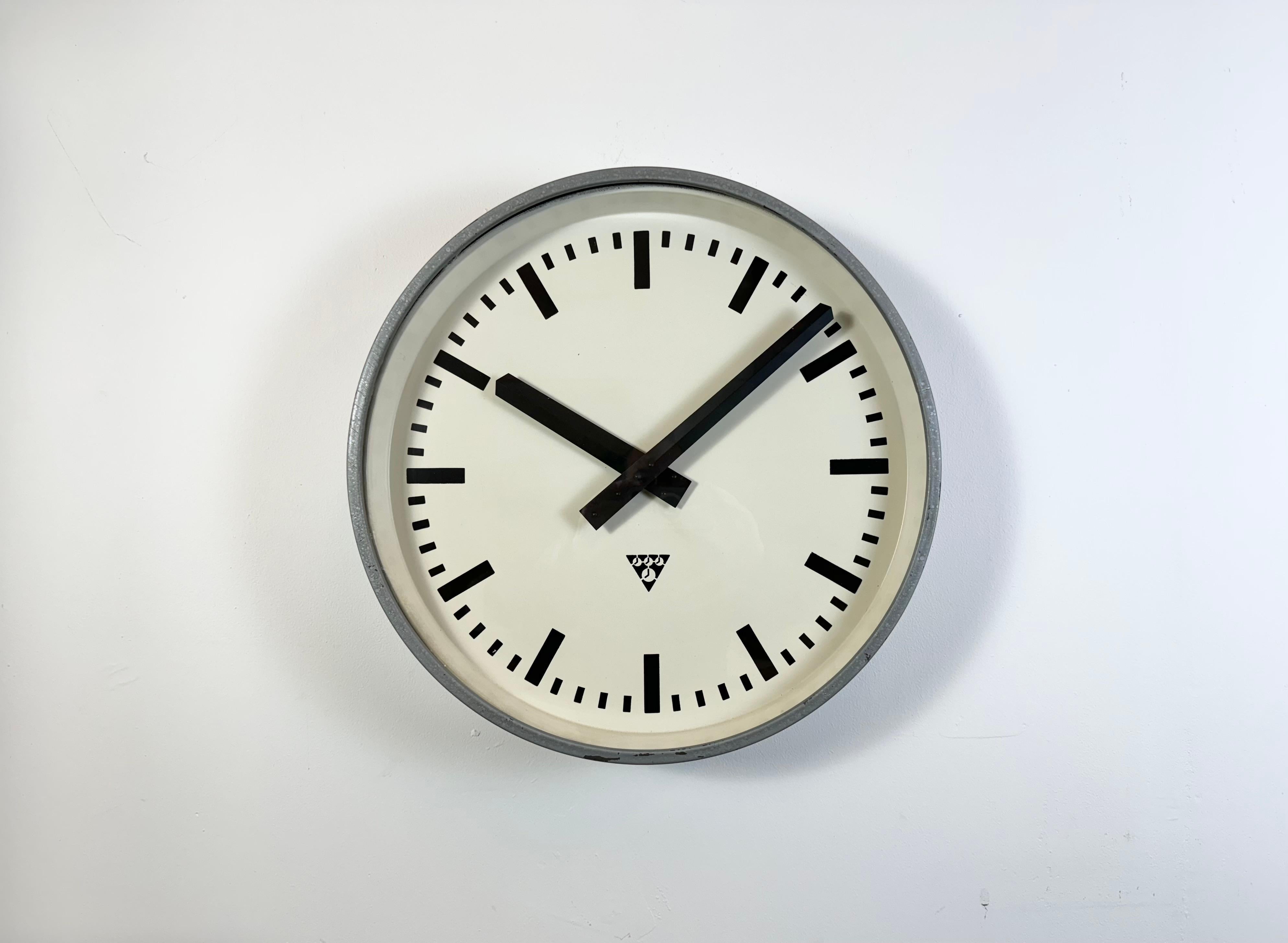 Cette horloge murale a été produite par Pragotron dans l'ancienne Tchécoslovaquie au cours des années 1960. Elle se compose d'un cadre en métal gris, d'un cadran en fer, d'aiguilles en aluminium et d'un couvercle en verre transparent. La pièce a été