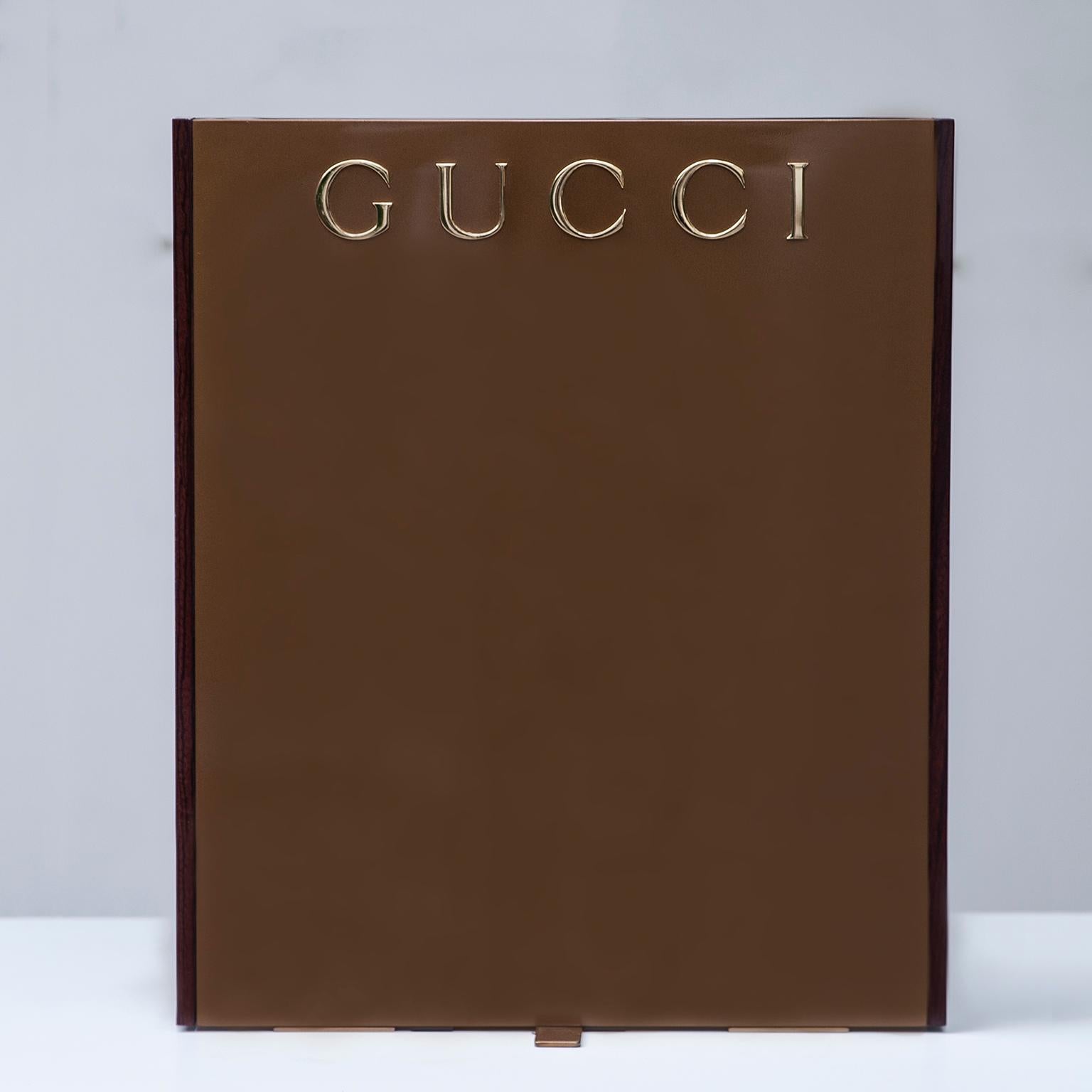 Elegant Gucci display in brown Lucite and golden metal stand.