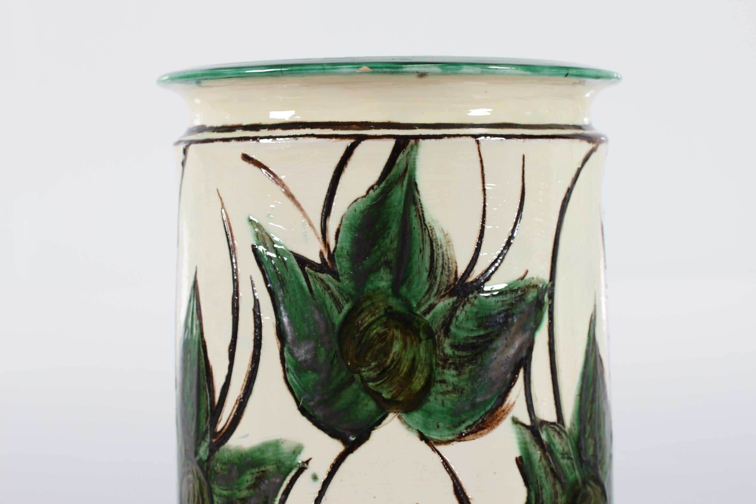 Huge and beautiful Danish ceramic floor vase made by Herman A. Kähler in the early 20th century (1915-1925).
The floor vase has a sand colored basecoat and a decoration with large green leaves.
The decoration is attributed to the painters Sofie
