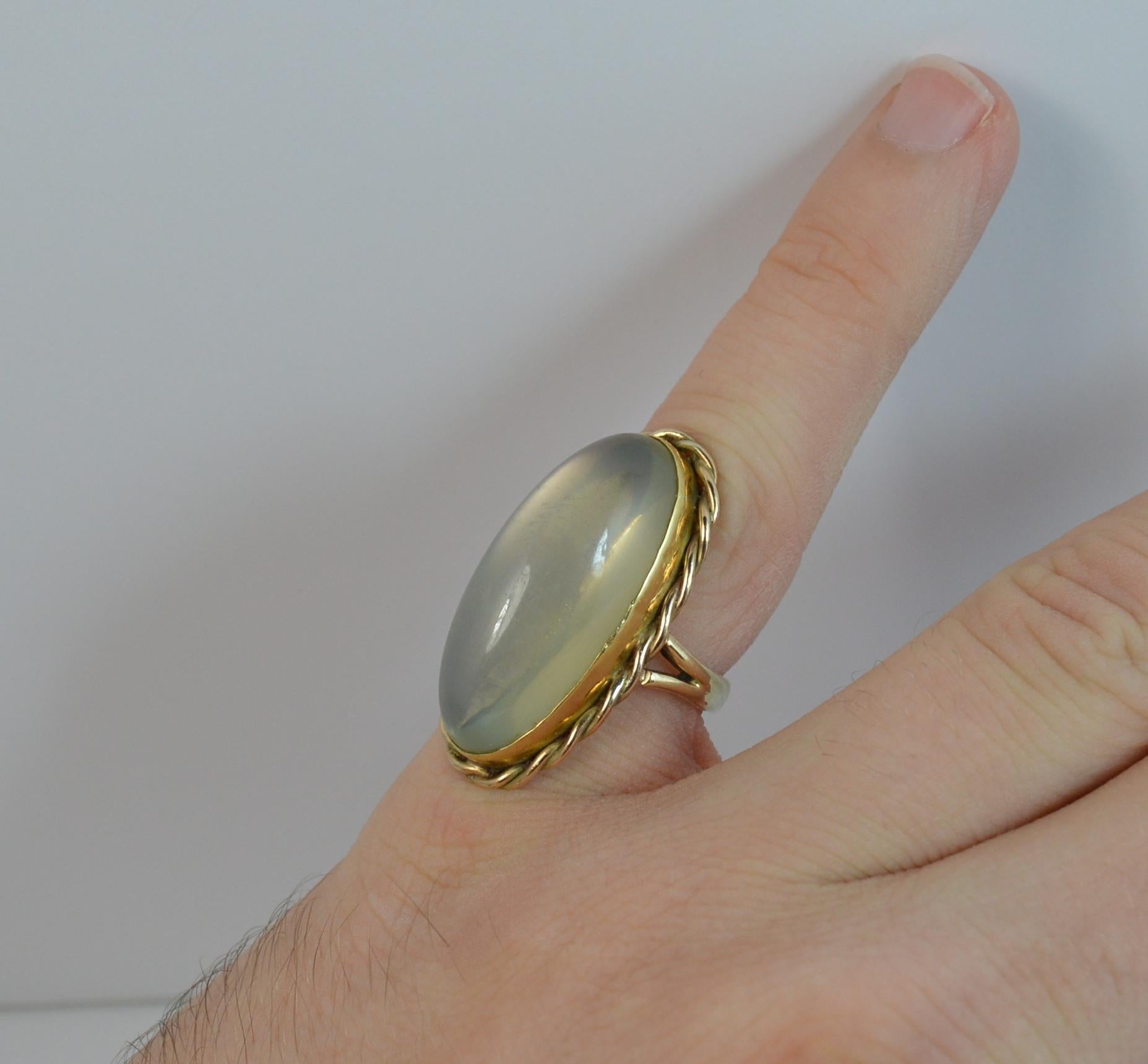 A fine retro solitaire ring. Solid 9 carat yellow gold example.
Size ; i UK, 4 US
Set with a single elongated oval moonstone agate cabochon, 13mm x 27mm approx with a gold rope twist surround to the bezel setting.



Condition ; Very good. Clean