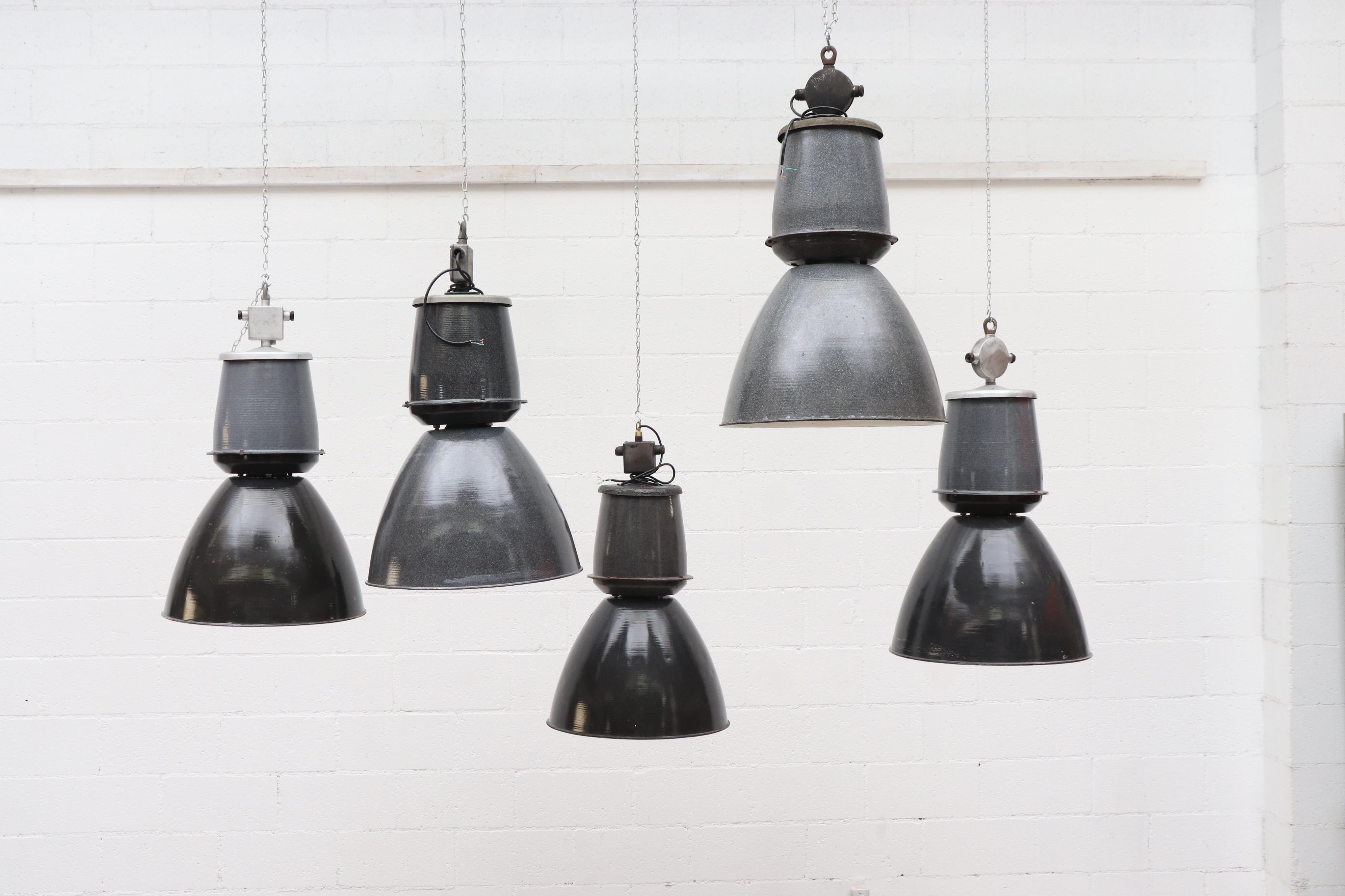 Industrial enameled factory ceiling lamps. Assorted speckled grey and dark charcoal shades and white enameled interior. Color combos vary per lamp. All in original condition with visible wear and minimal chipping consistent with their age and usage.