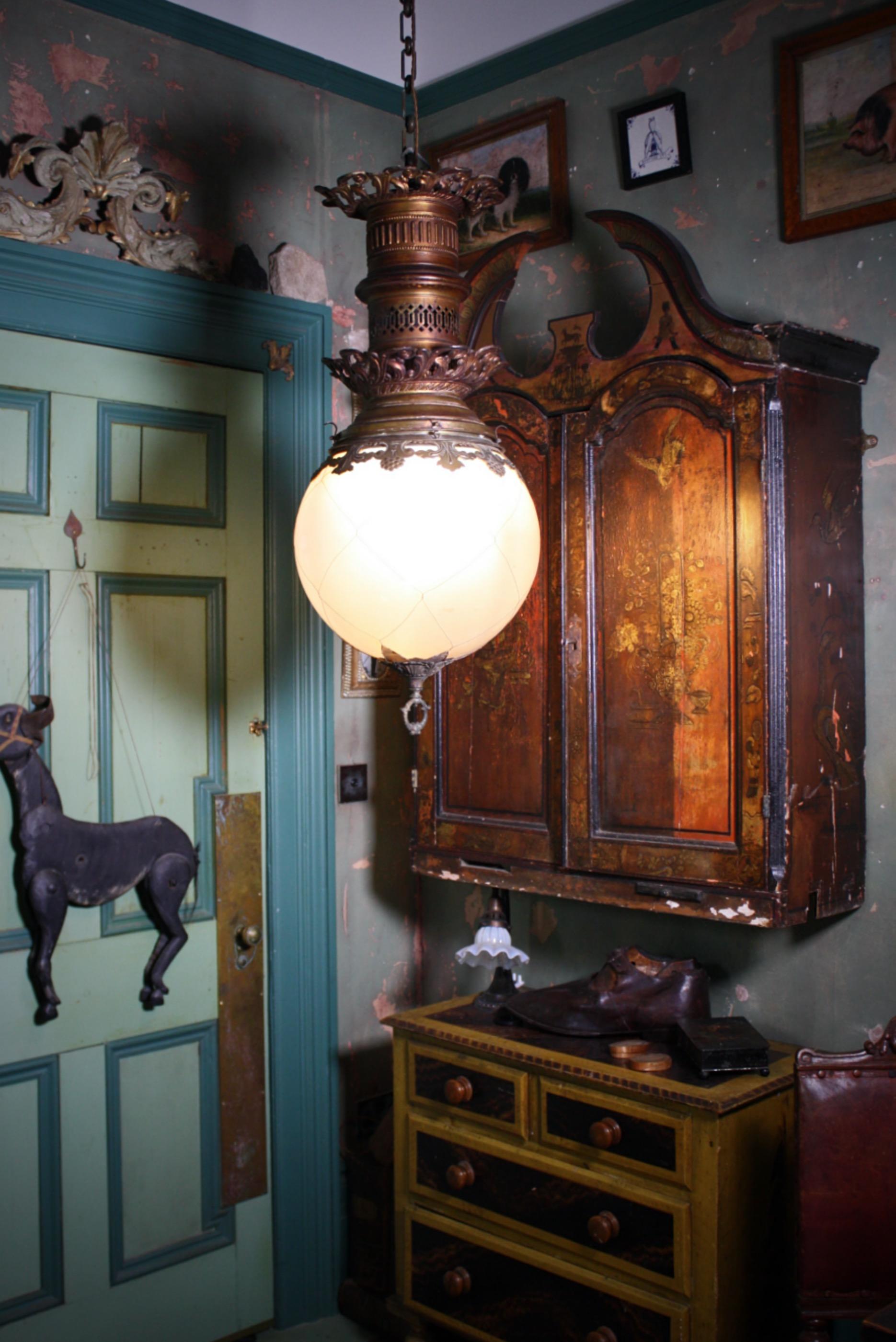 An extra large turn of the century French converted gas light, with elongated pressed gilt brass gallery, and opalescent glass globe.

The glass globe has a protective wire cage, with a cast brass gilt hooped finial. 

The finial is attached to