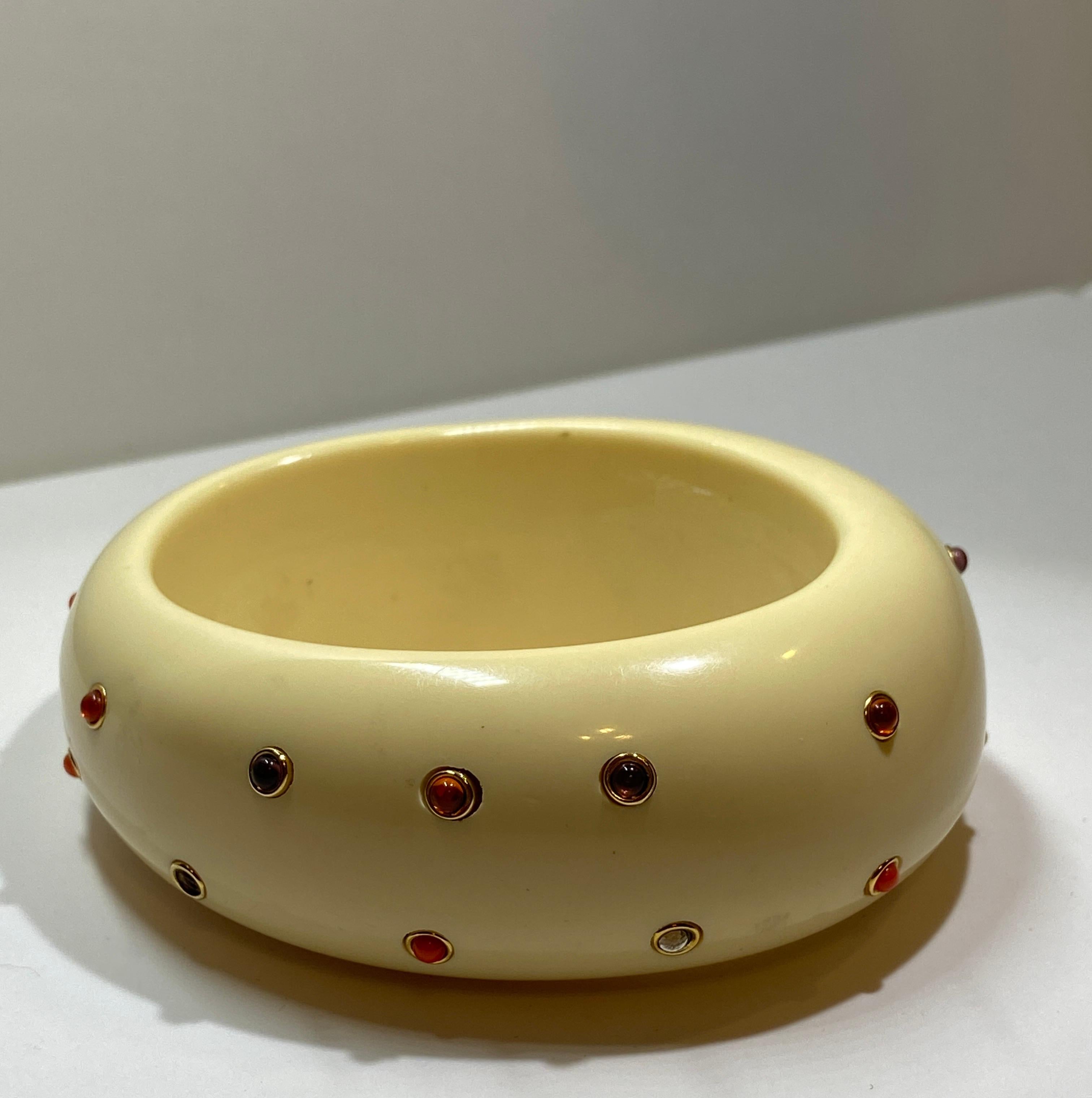 Huge Whimsical Lee Angel's cream lucite ivory-like bangle is accented with micro-size multi-colored semi-gems in colors of coral, reds, diamonds and purples. There are 3 stones missing but hardly noticeable. The interior circumference measures 7 3/4