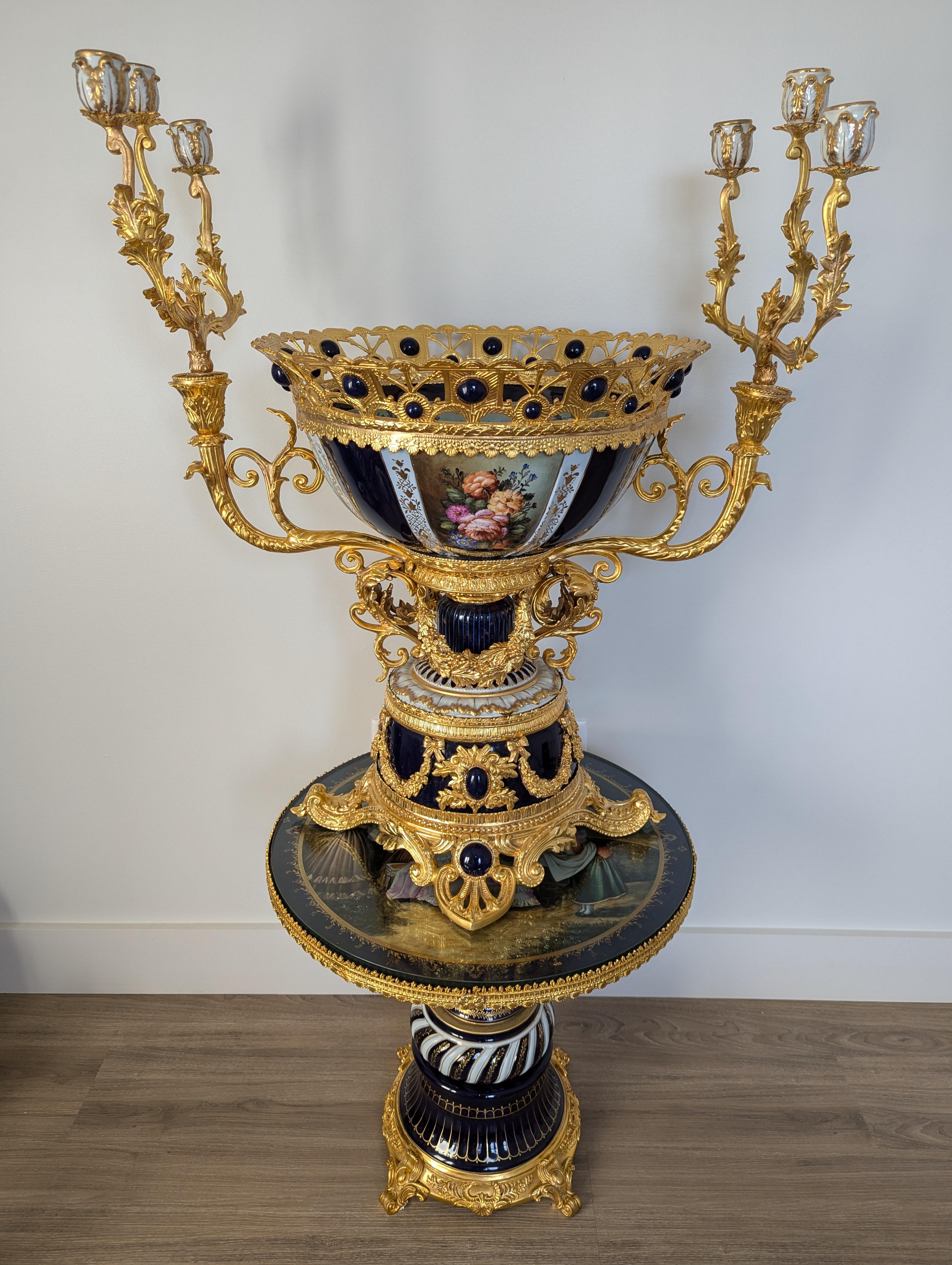 Cette extraordinaire coupe candélabre de style Grandeur Louis est une véritable pièce d'apparat, incarnant la grandeur et l'opulence du design français du XVIIIe siècle. D'une hauteur impressionnante de 36 pouces et d'un diamètre de 28 pouces, ce