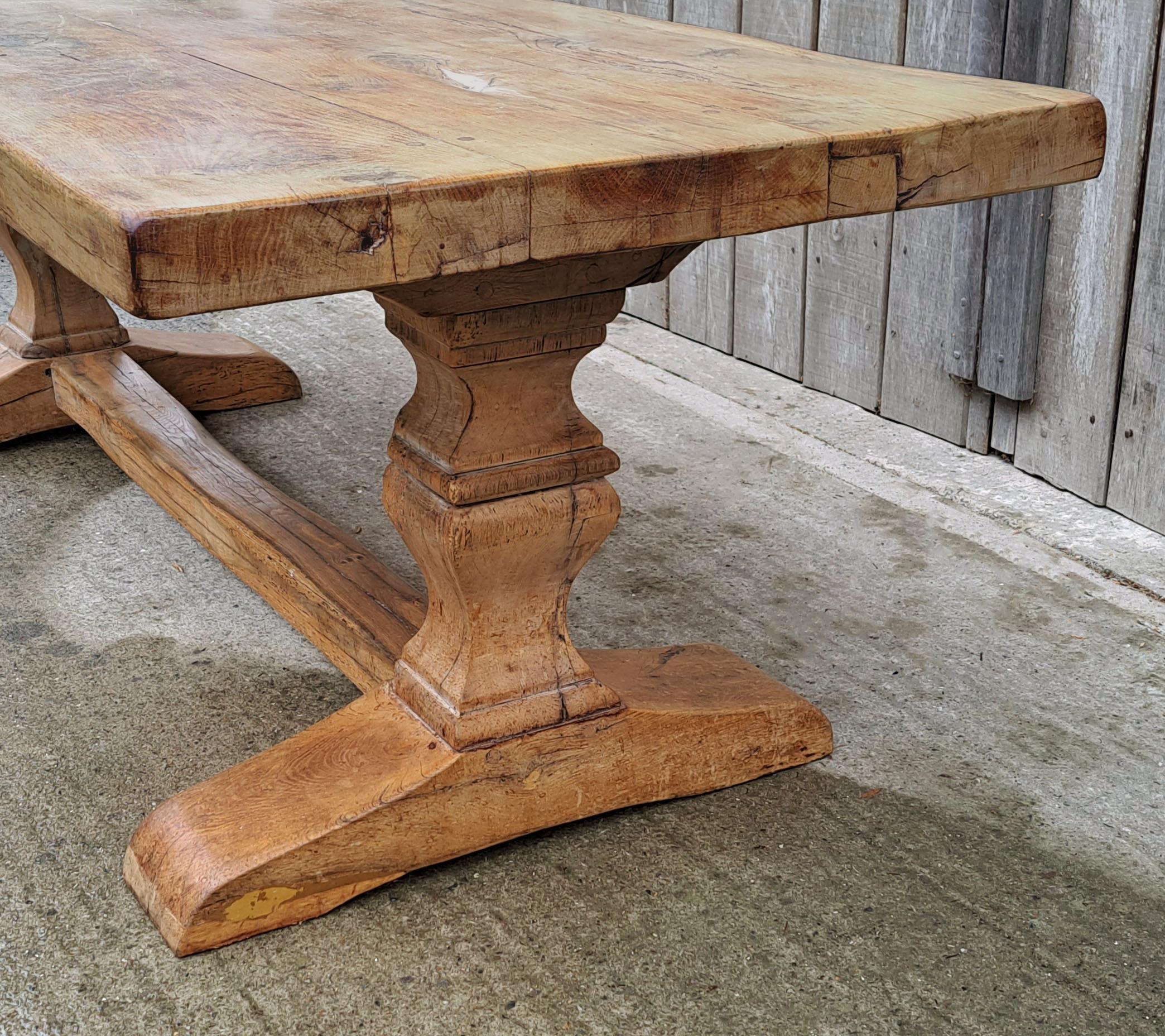 Reputedly from a monastery, this huge and impressive table is solid oak and is exceptionally heavy and beautiful.

The enormous slab top comprises three 2.75 inch deep single boards, peg jointed to the well shaped trestle legs on sleigh feet.   The