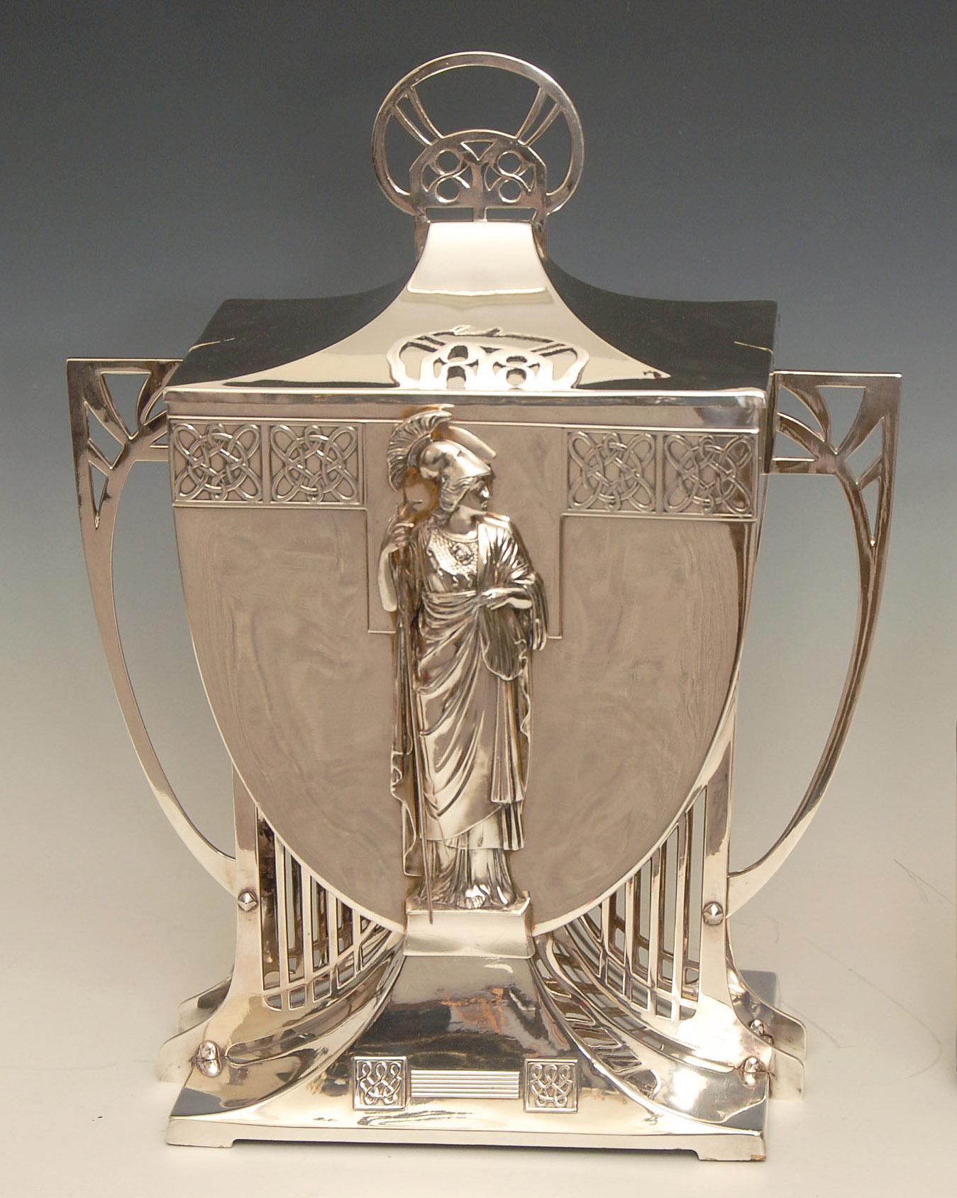 Stunning WMF Art Nouveau Ice Bucket / Centrepiece with lid depicting a female warrior with spear.
Made by the WÜRTTEMBERGISCHE METALLWARENFABRIK factory in Germany around 1910 possible as an exhibition piece.

20 inches high, price includes free