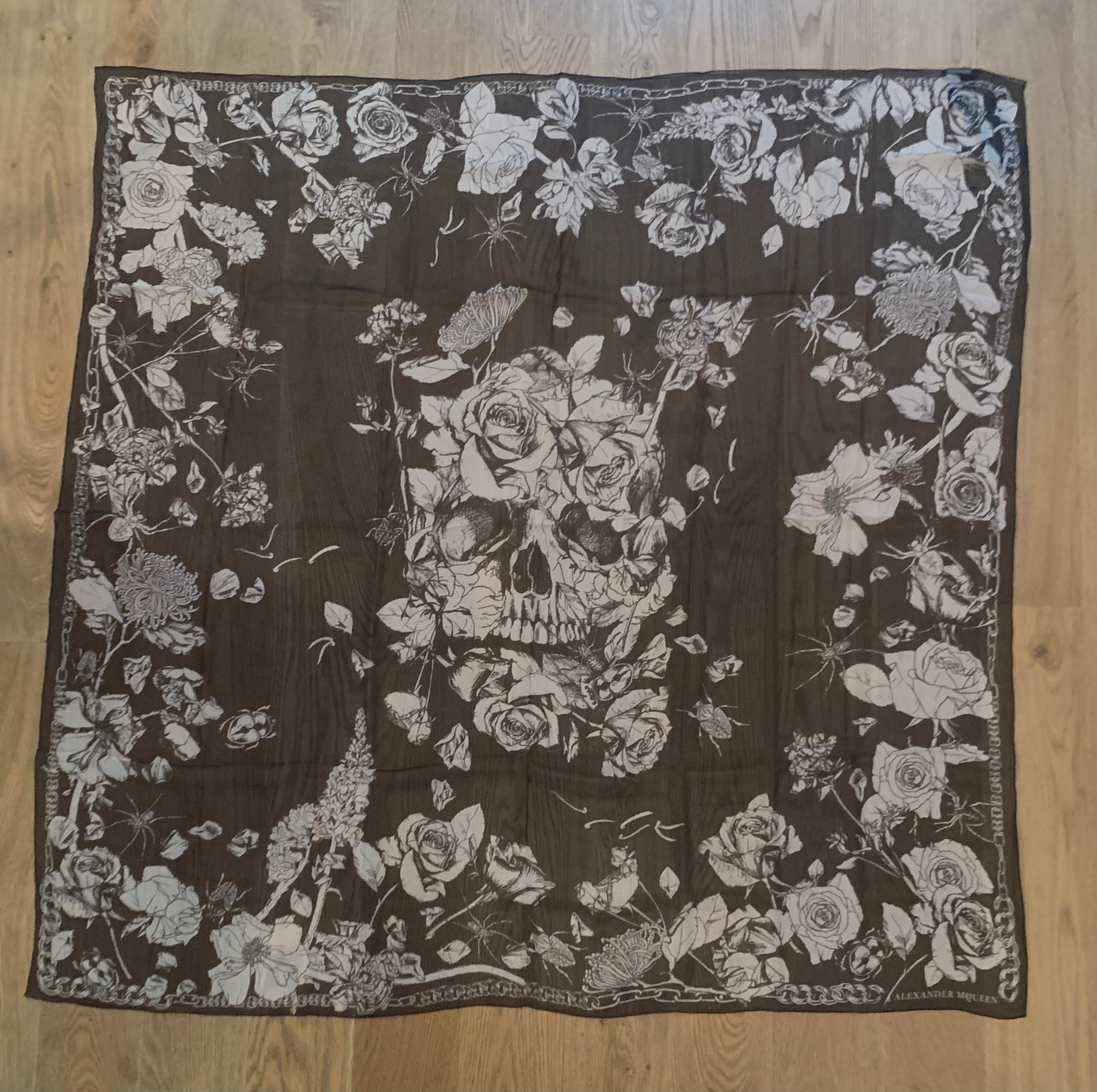 New Alexander McQueen large semi-sheer black and white silk chiffon scarf featuring a skull at center with roses and insects throughout, chain print around border. Signed Alexander McQueen at bottom right corner.

Large size makes it great for a