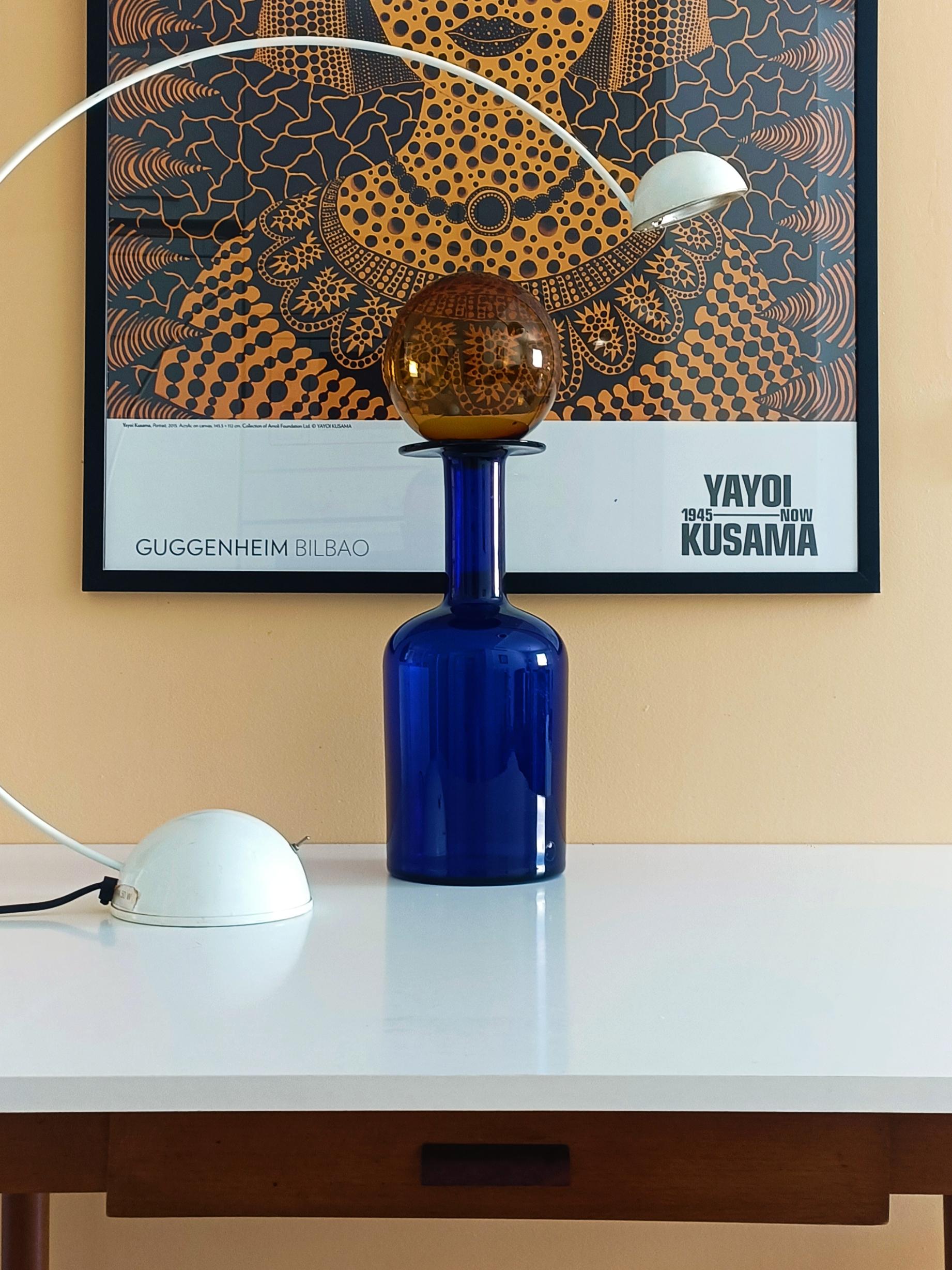 A stunning vintage glass bottle by Otto Brauer for Holmegaard, a true statement of Mid-Century Danish design. Hand-blown in Denmark around the 1960s, this enormous cobalt blue bottle with its eye-catching huge amber ball stopper is a rare find. Its