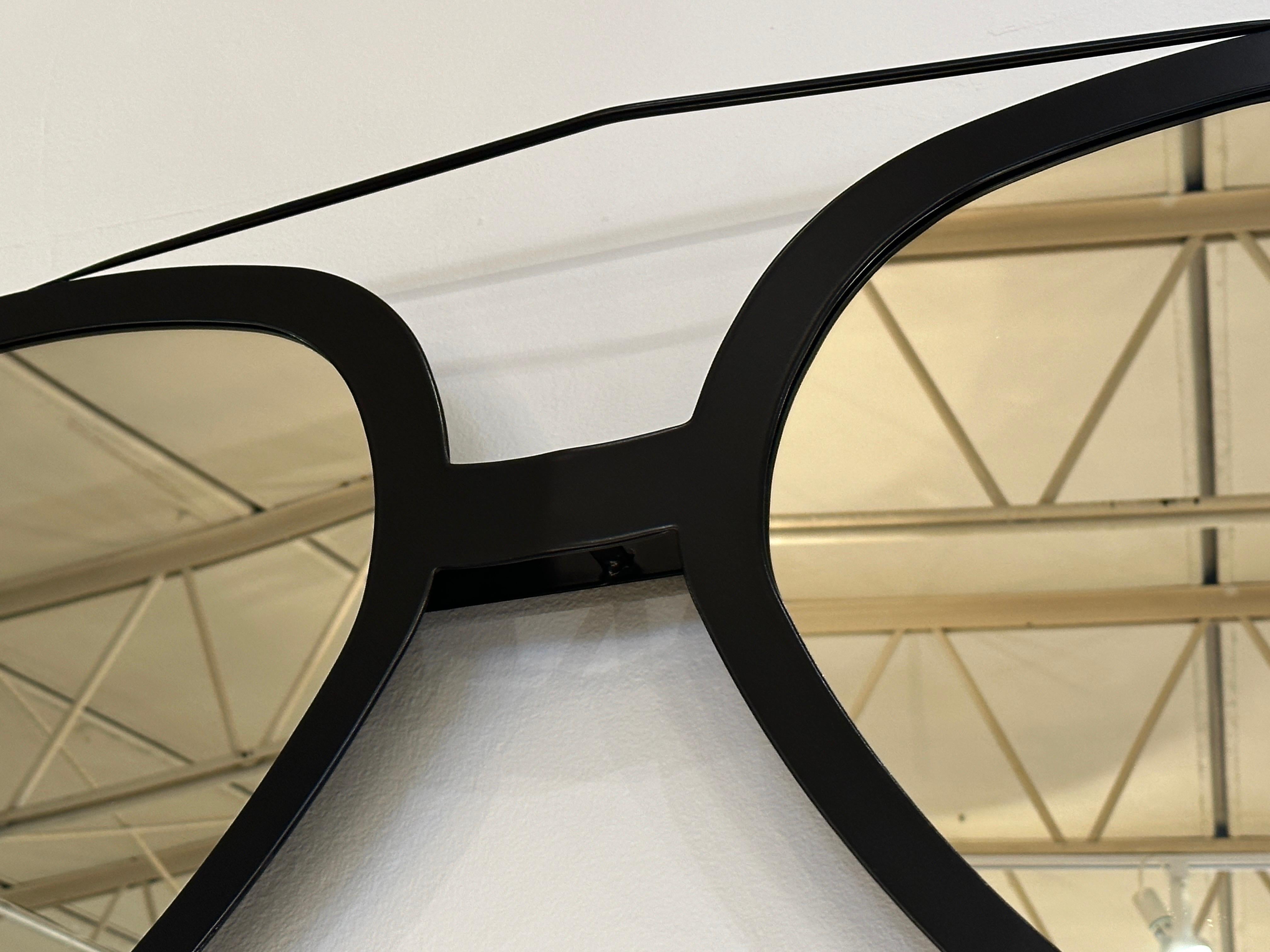 Ce miroir de lunettes de soleil Aviator surdimensionné, au revêtement en poudre noir mat, est d'une qualité artisanale exquise et constitue un choix de décoration très fantaisiste pour n'importe quel espace. Nouvellement recouvert d'une couche de