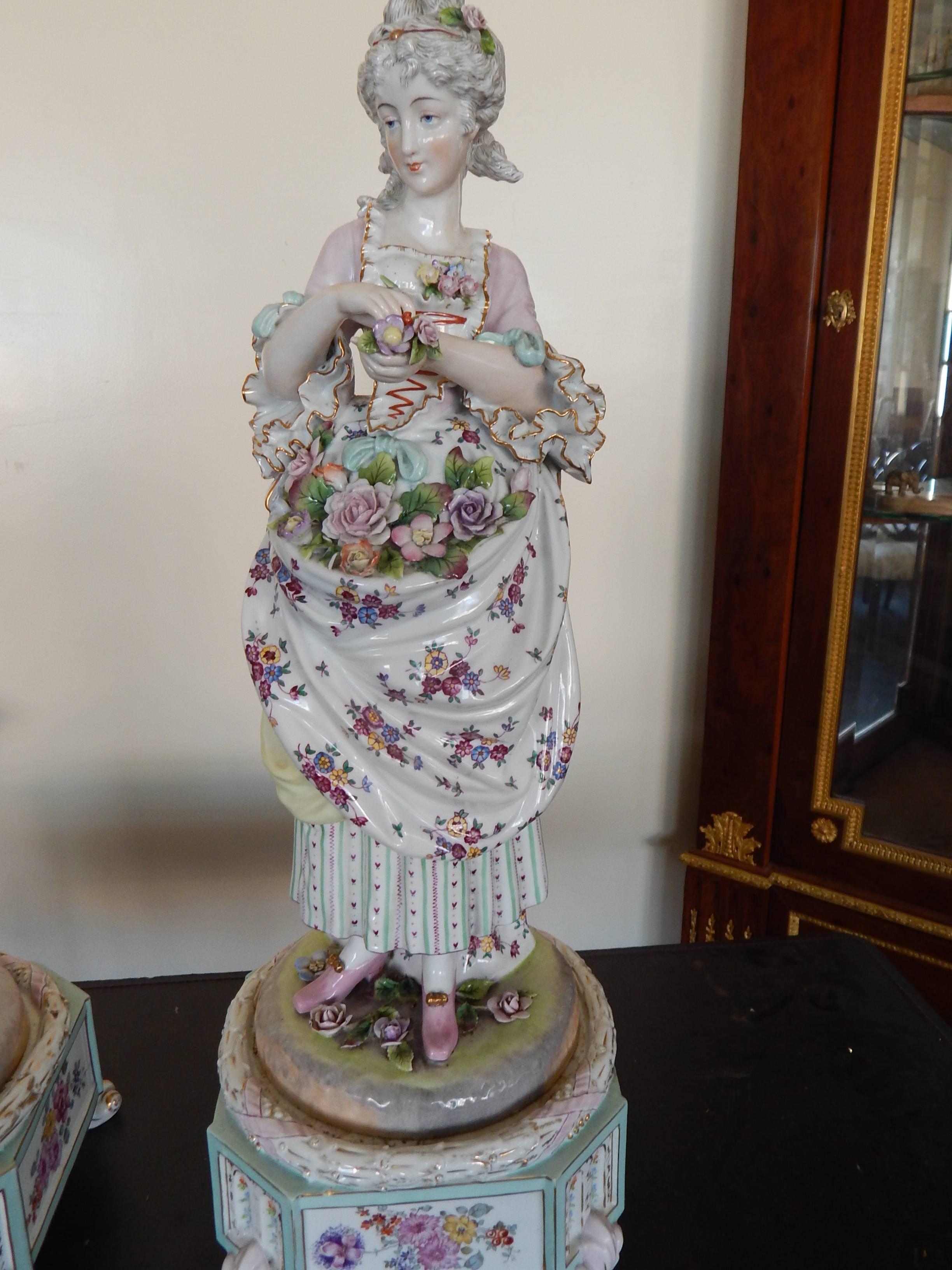 A large and impressive pair of hand-painted porcelain figures on plinths of a man and woman if formal 18th century attire.
Likely German, with painted numbers on the bottom.
These were once lamps, so there is a hole in the back of each.
There is