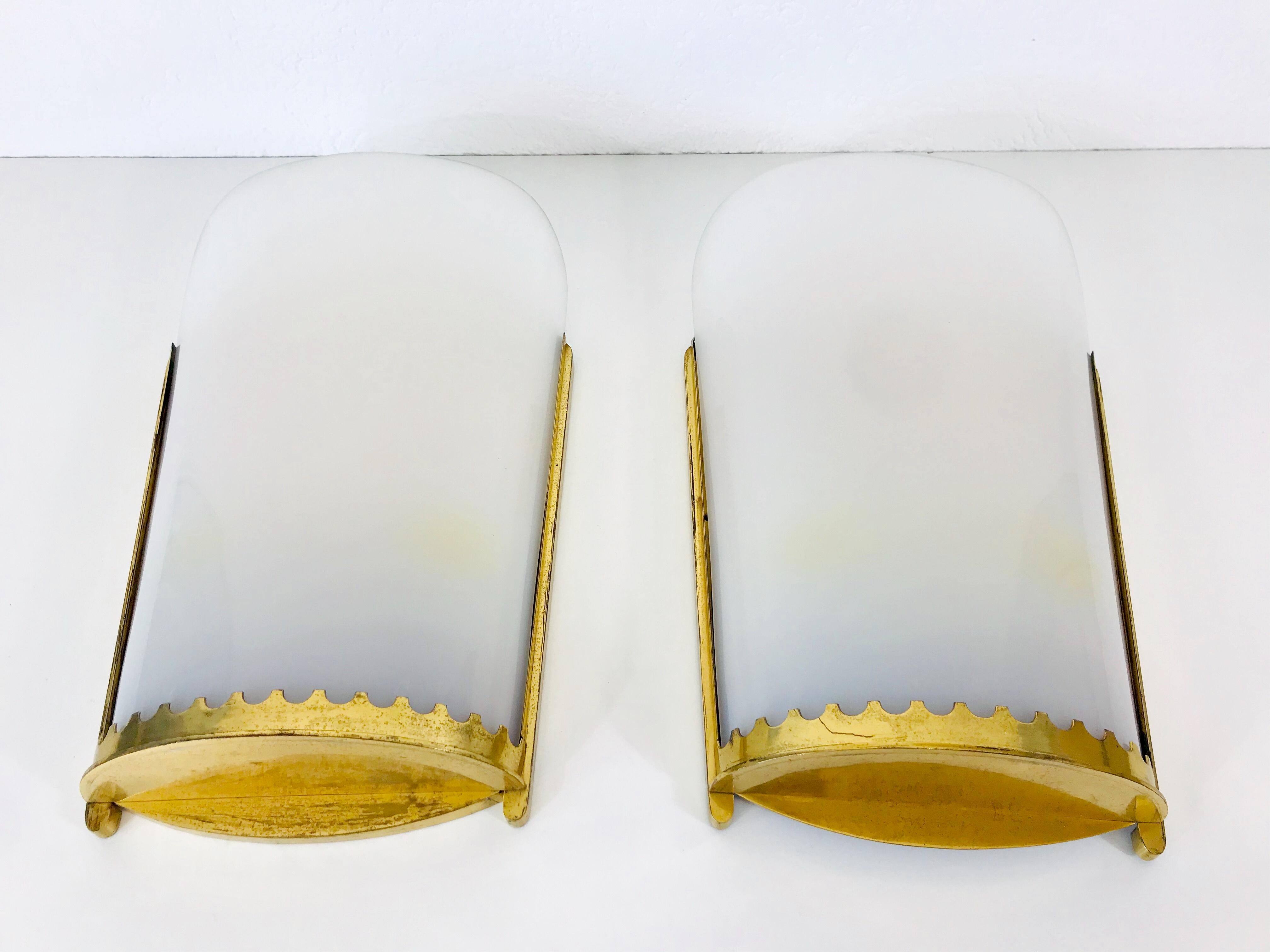 A pair of very large Mid-Century Modern wall lamps made in the 1950s.. They can perfectly be mounted on the wall. The shade of the lights is made of white perxpex with a brass frame.

The light requires three E27 light bulbs. Good vintage